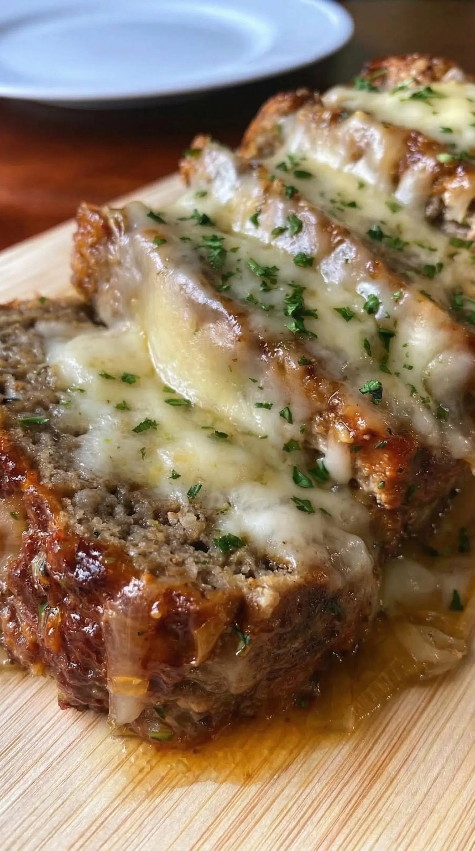 A slice of meat with cheese on top.
