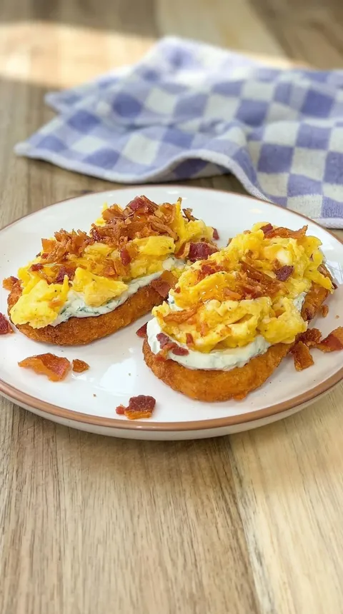 Two pieces of bacon and egg on a plate.