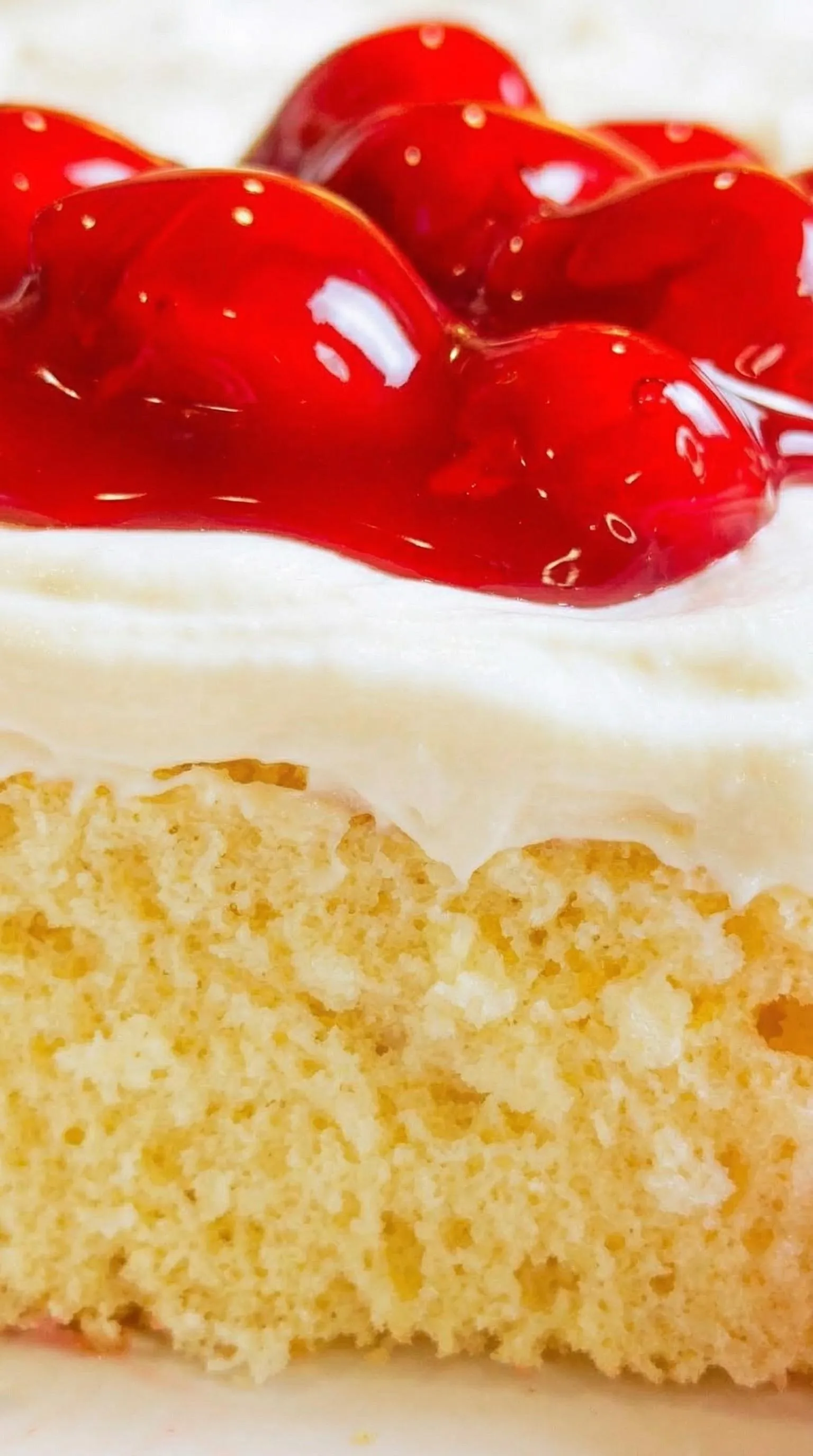 A slice of cake with red strawberry topping.