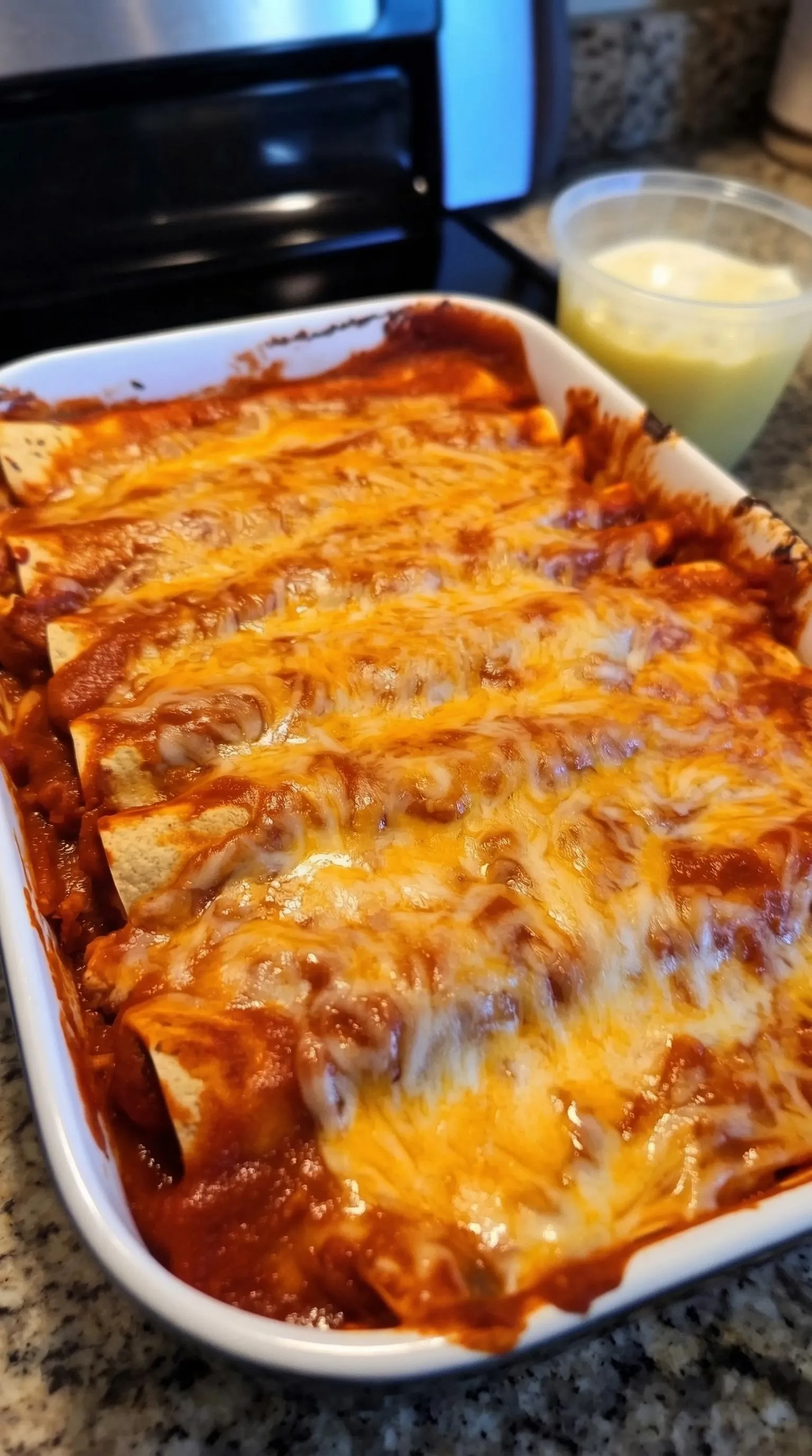 A white bowl with a cheese and chili covered burrito.