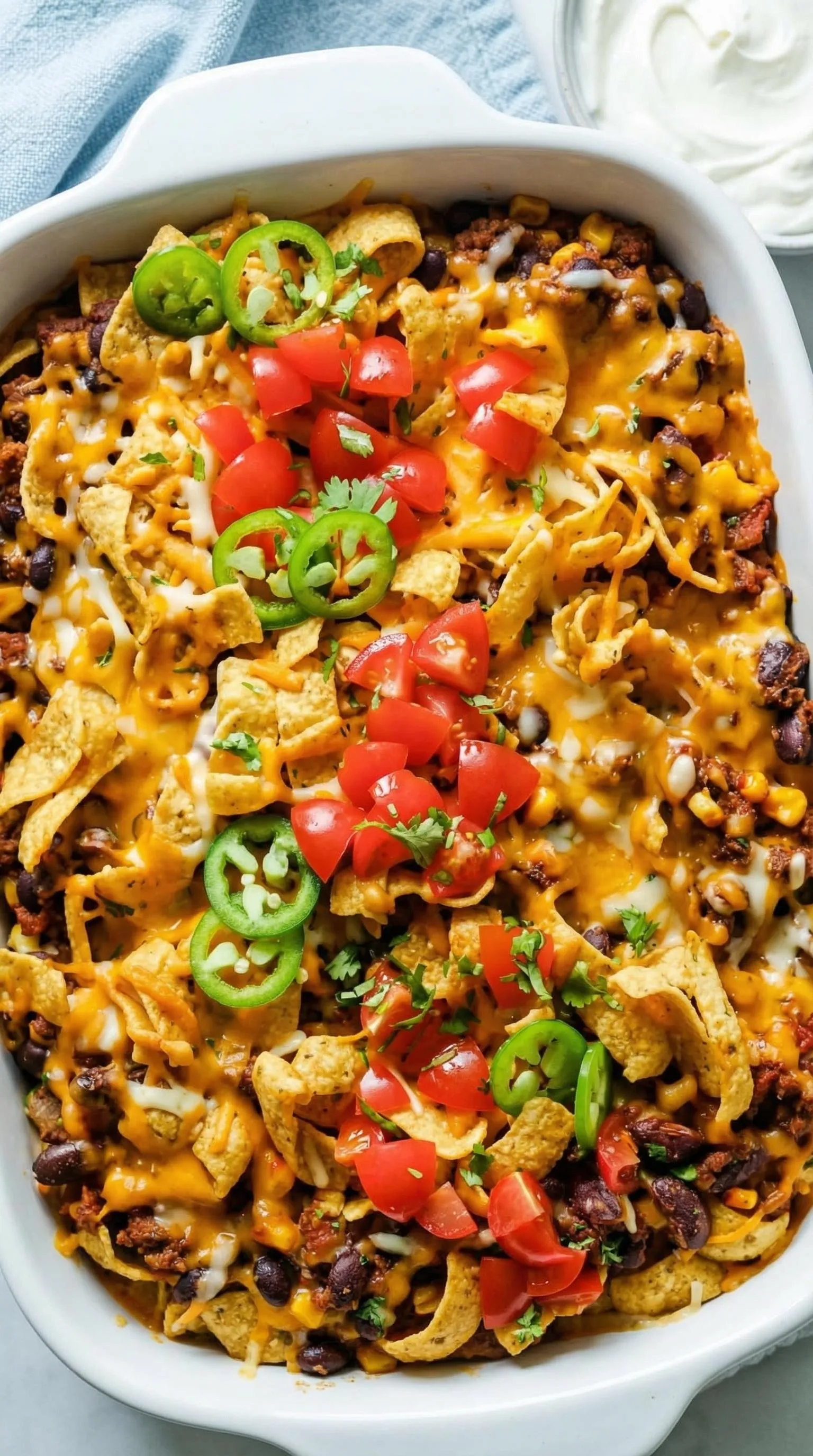 A dish of nachos with tomatoes and jalapenos.