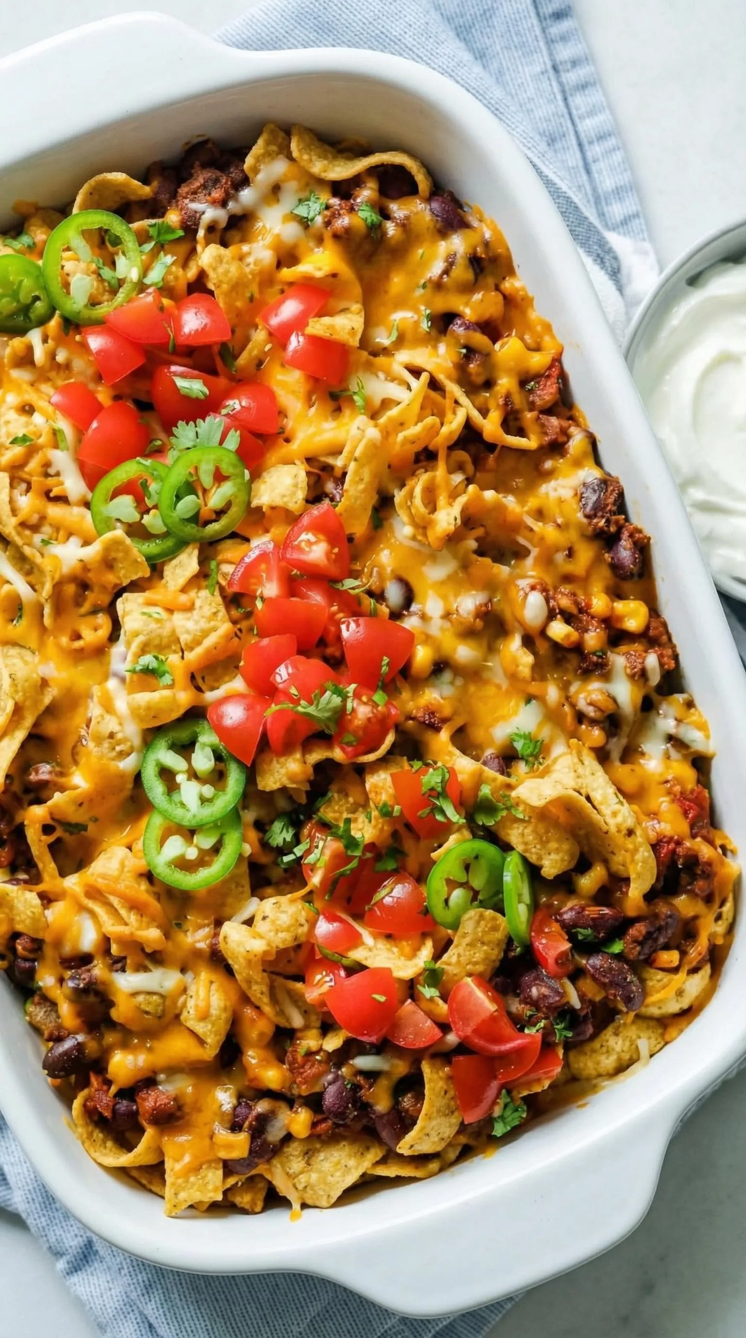 A dish of nachos with tomatoes and jalapenos.