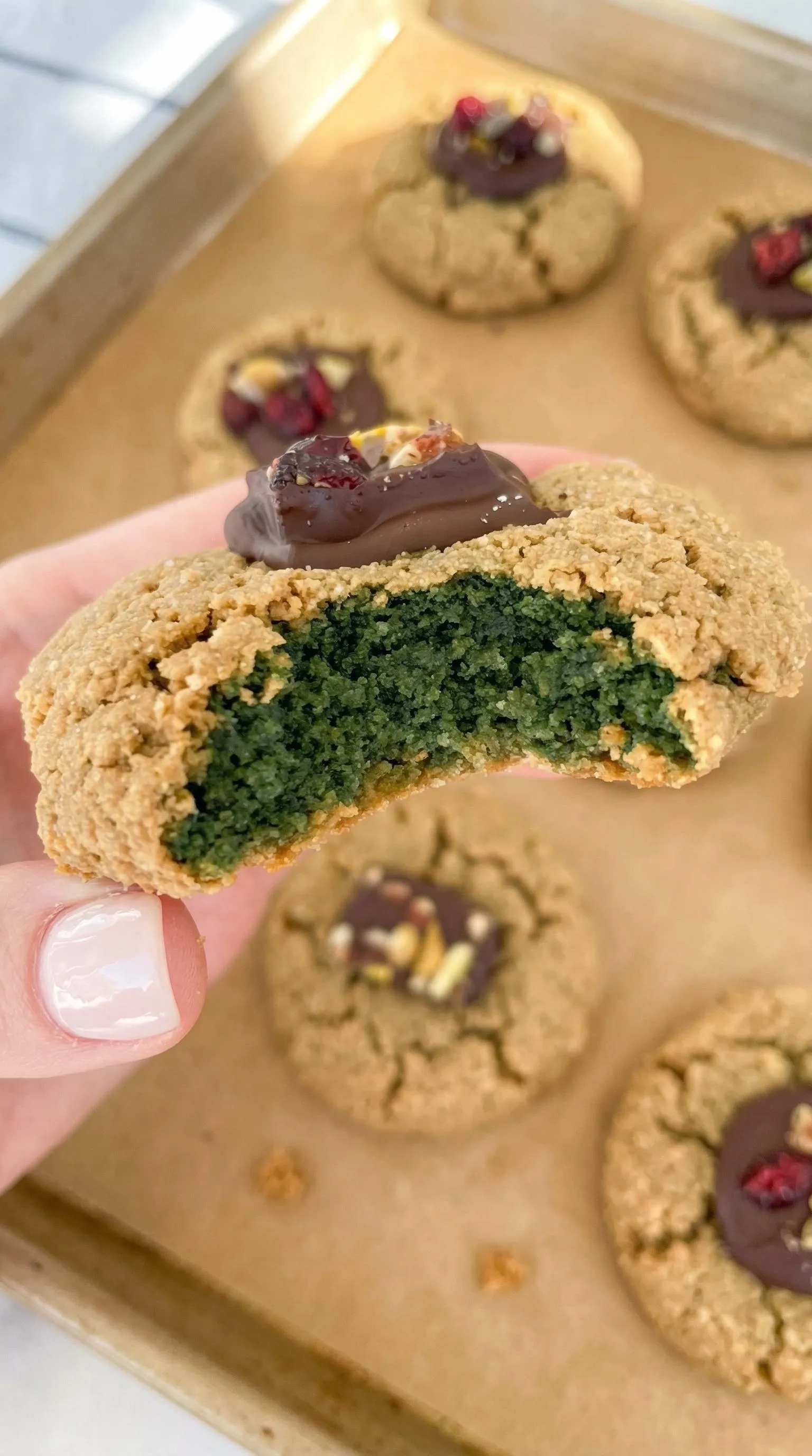 A person holding a cookie with chocolate and green icing.