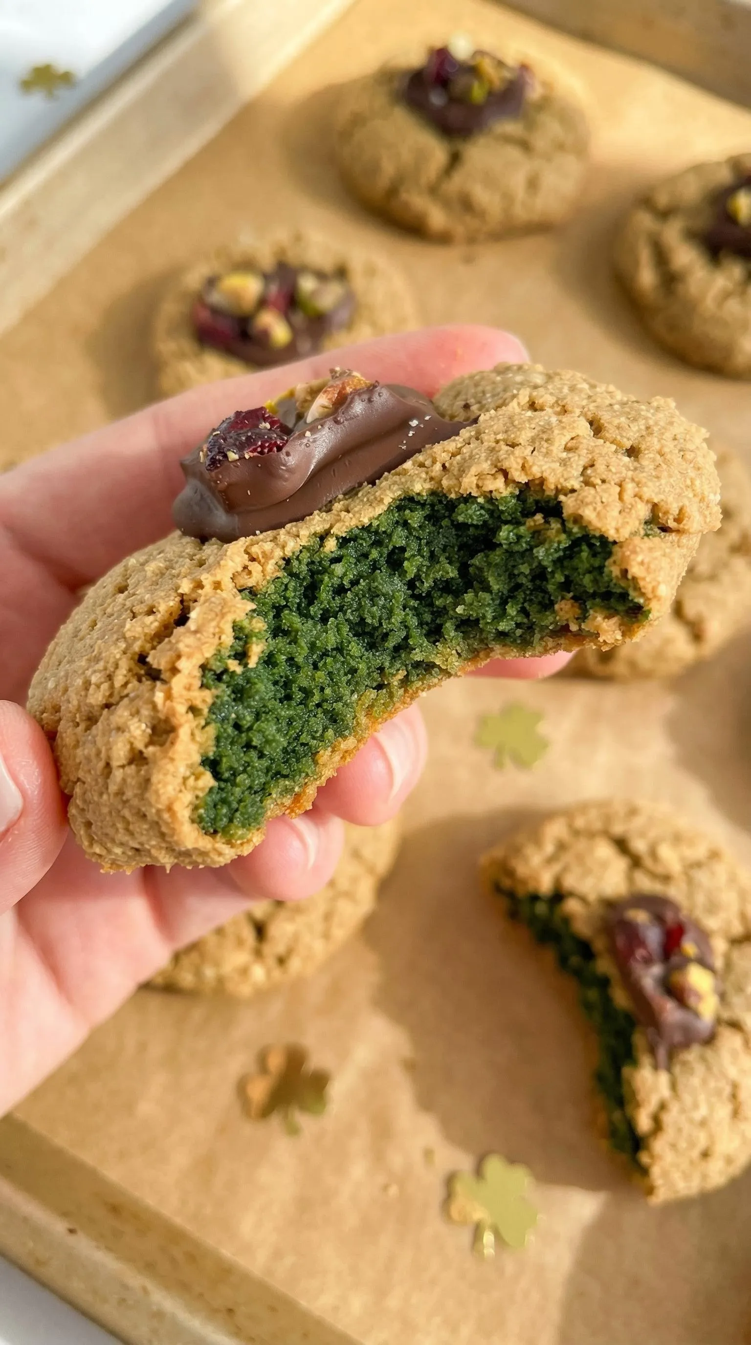 A person holding a cookie with green icing.