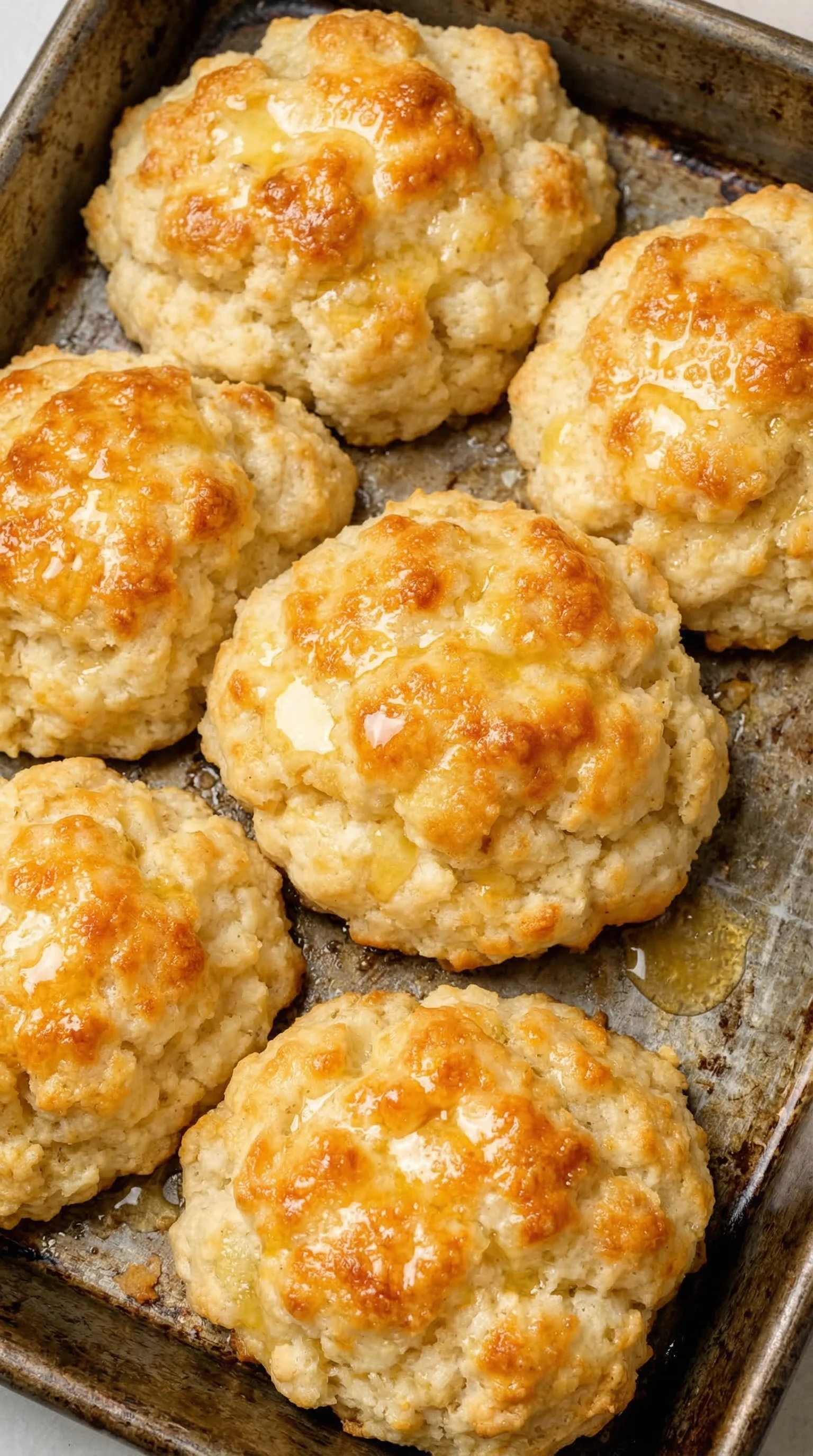 A tray of biscuits with butter on top.