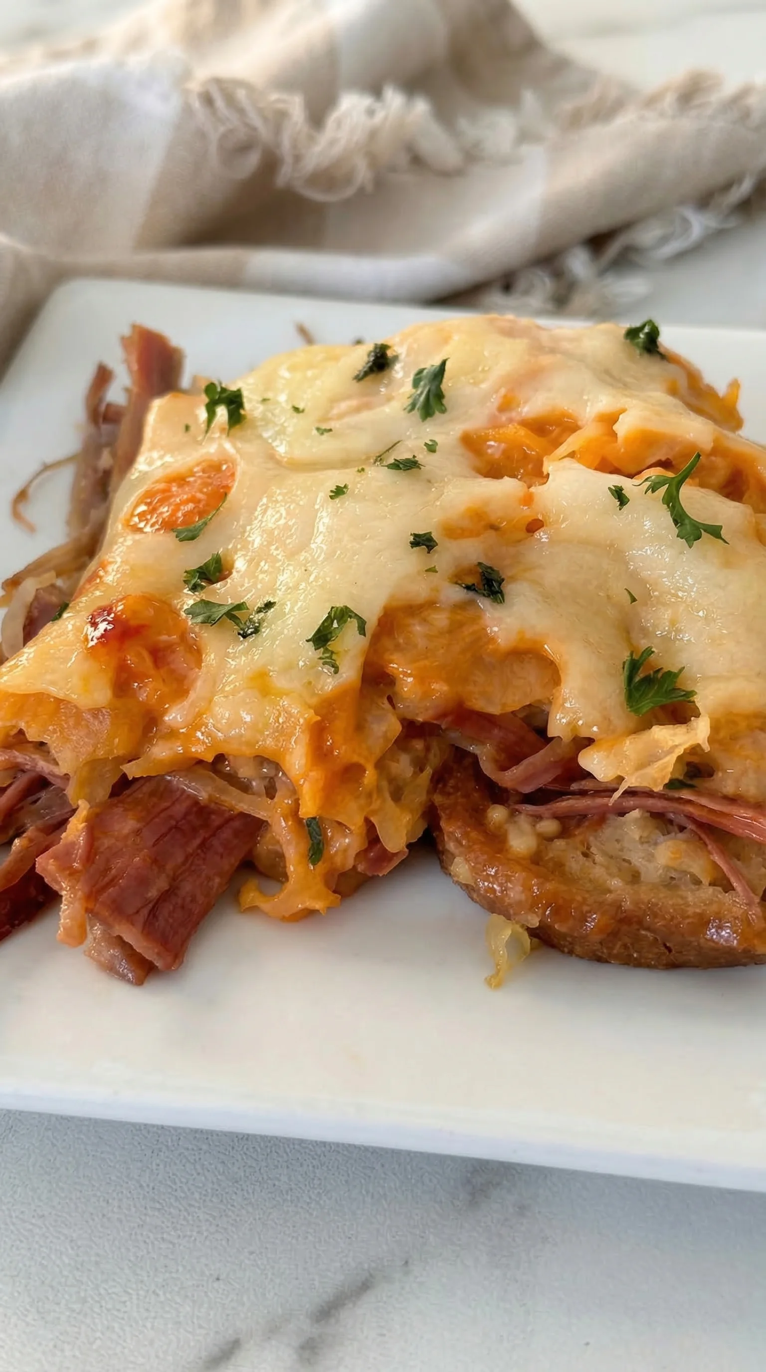 A slice of meat with cheese on a white plate.