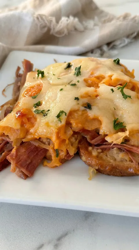 A slice of meat with cheese on a white plate.