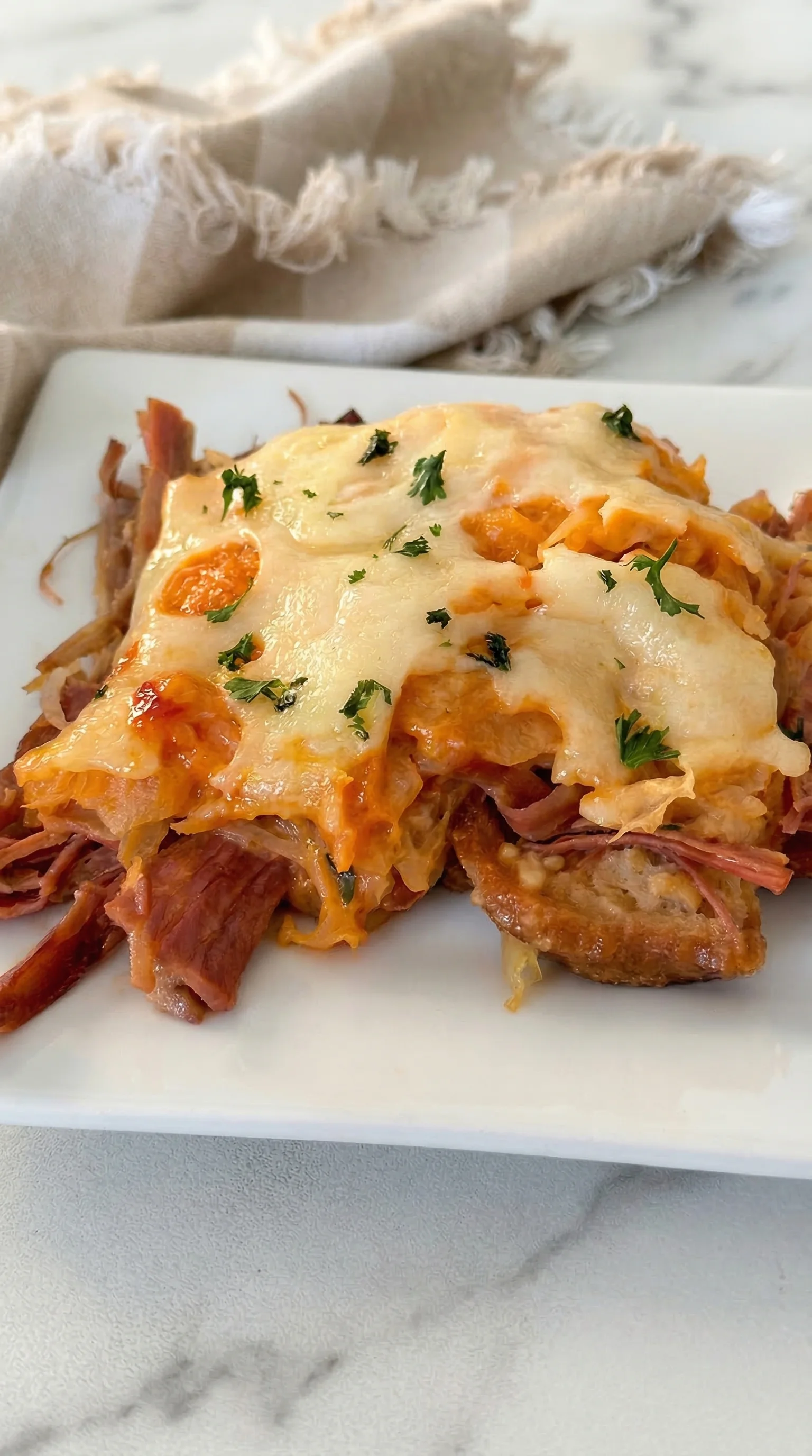 A white plate with a slice of meat and cheese.
