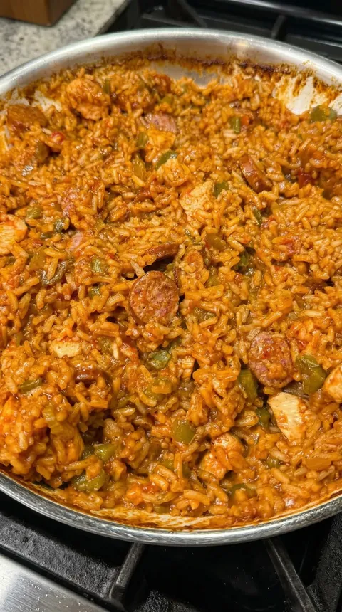 A bowl of rice with sausage and peppers.