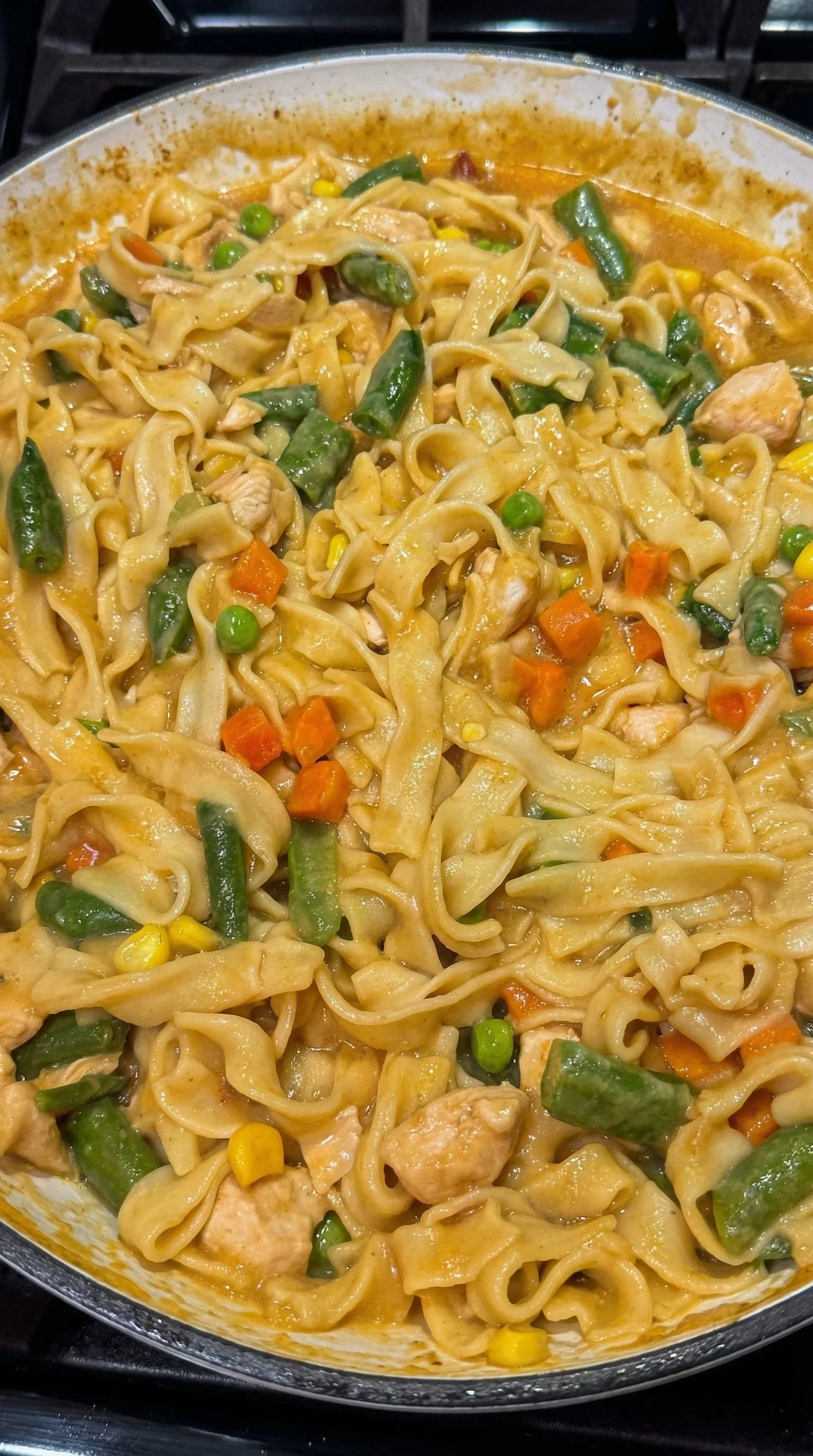 A plate of food with noodles, carrots, and peas.