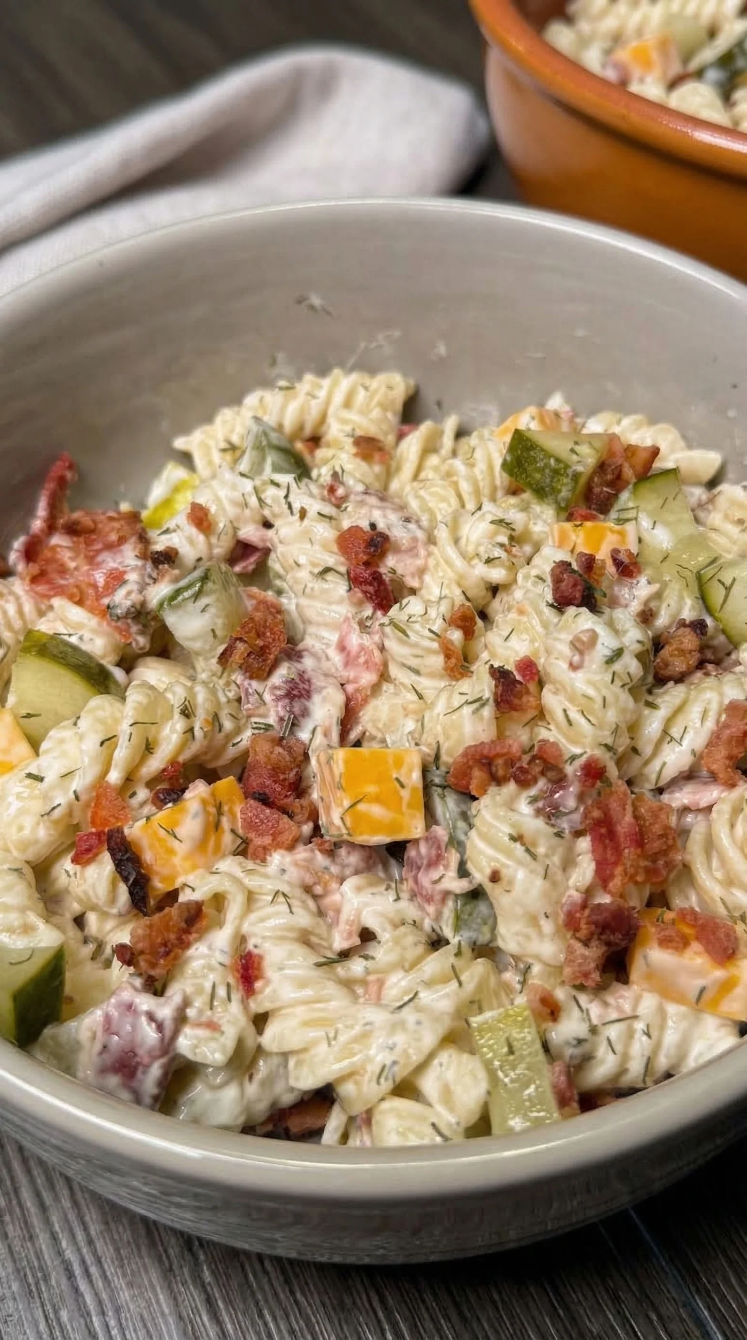 A bowl of pasta with vegetables and bacon.