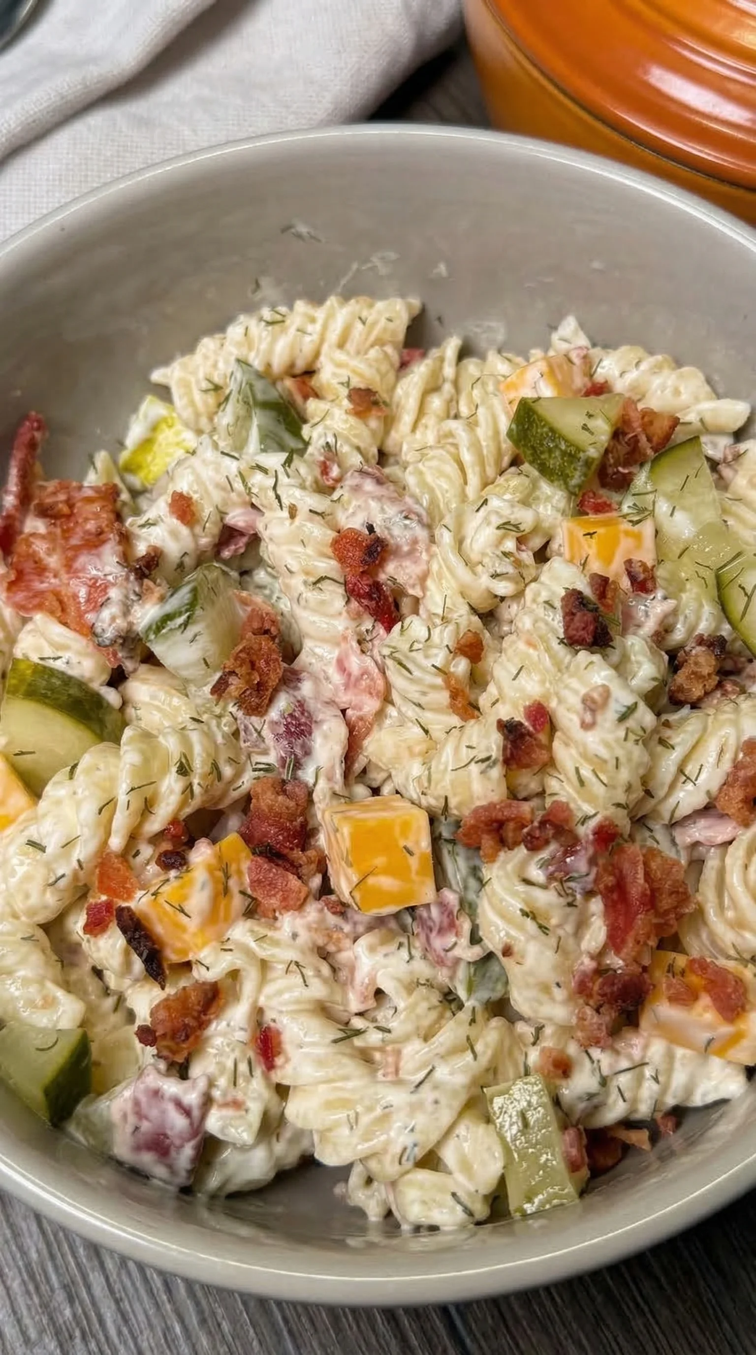 A bowl of pasta with vegetables and bacon.