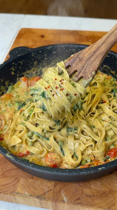 A wooden spoon is being used to scoop food from a bowl.