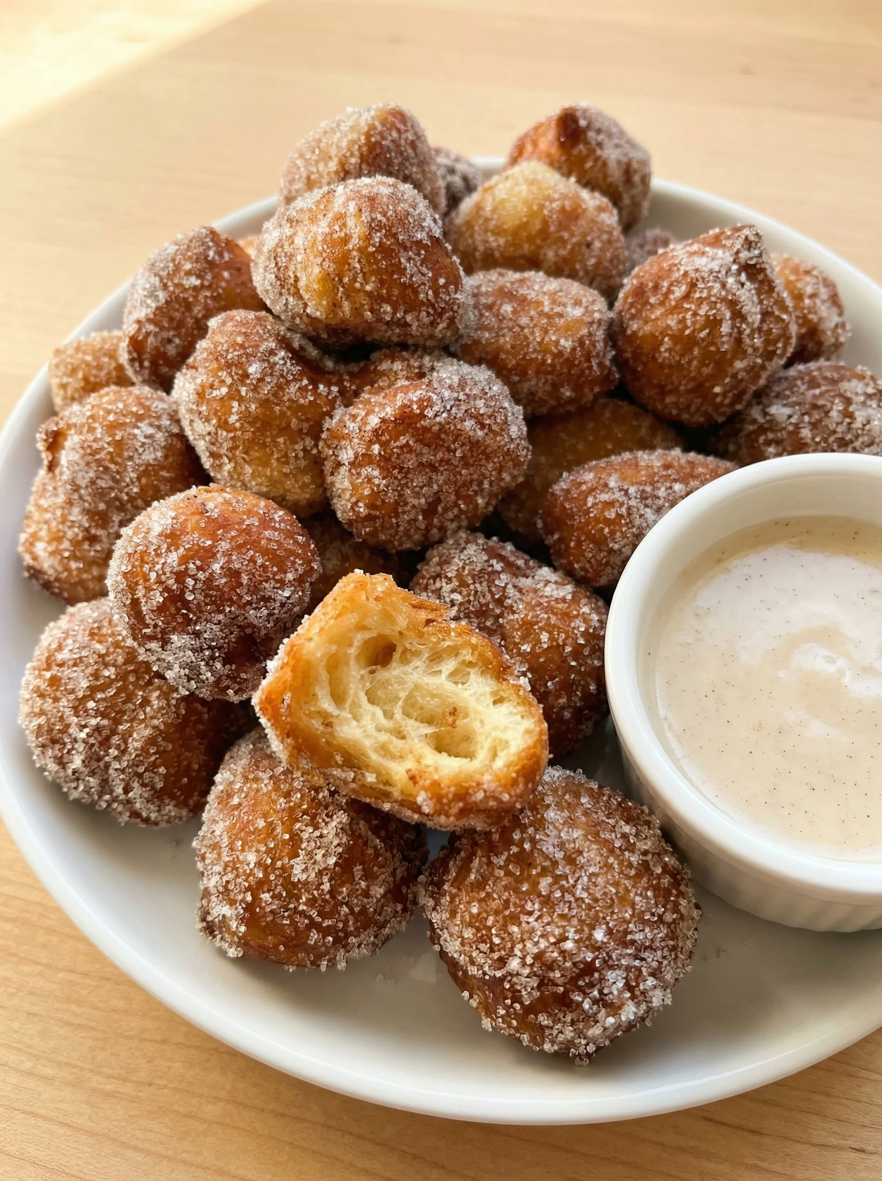 A plate of doughnuts with a cup of sauce.