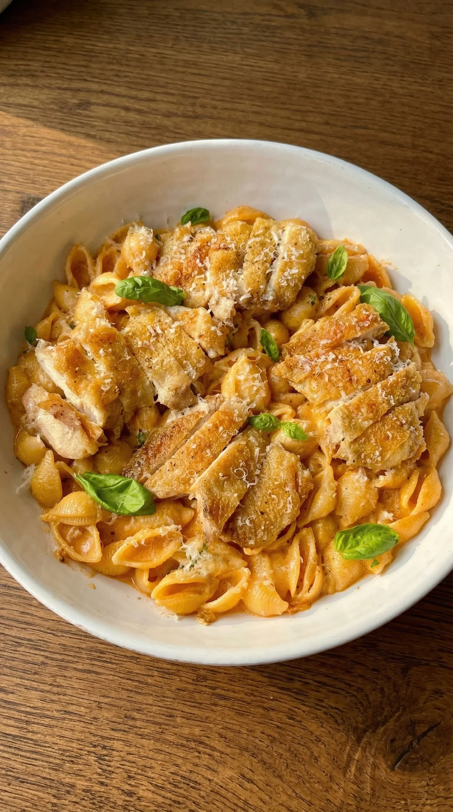 A bowl of pasta with chicken and spinach.