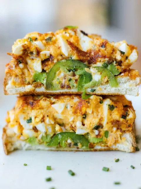 A sandwich with egg salad and jalapenos.
