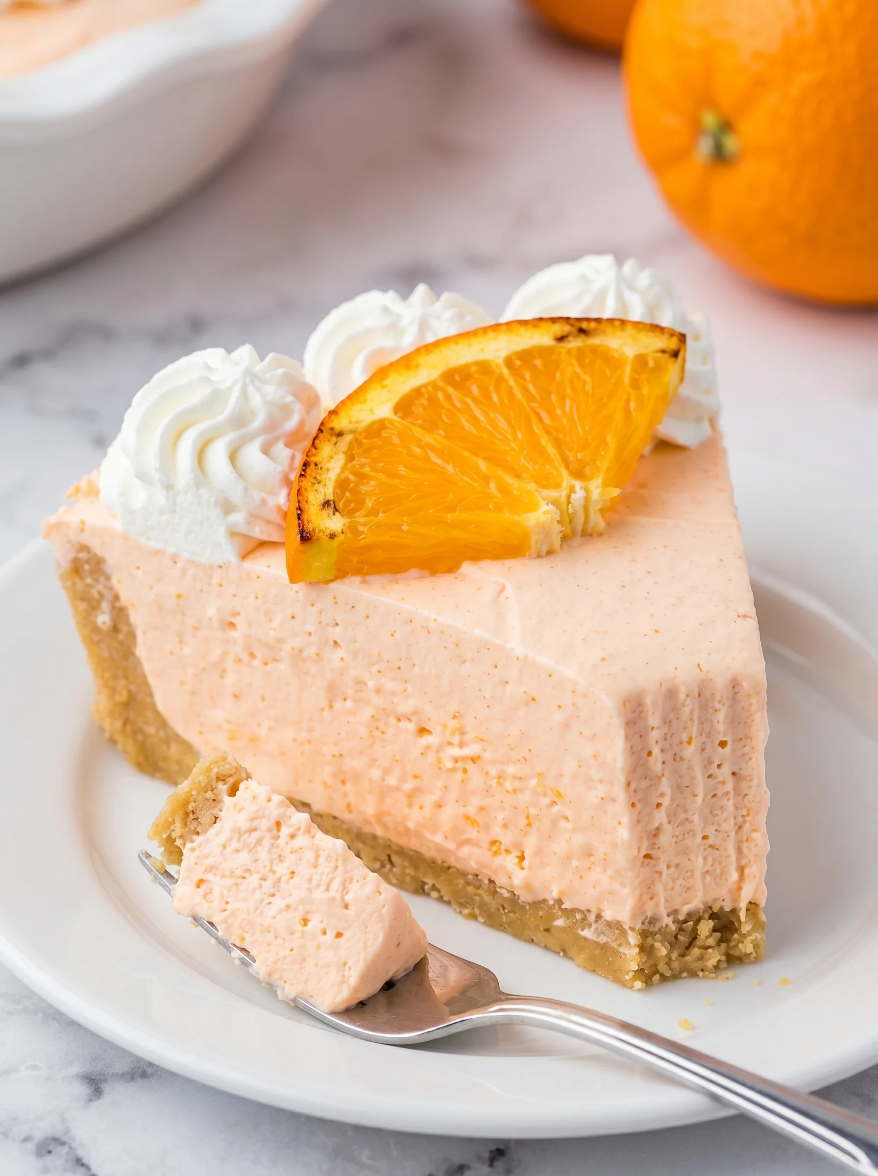 A slice of Jello Creamsicle Pie with a orange wedge on top.