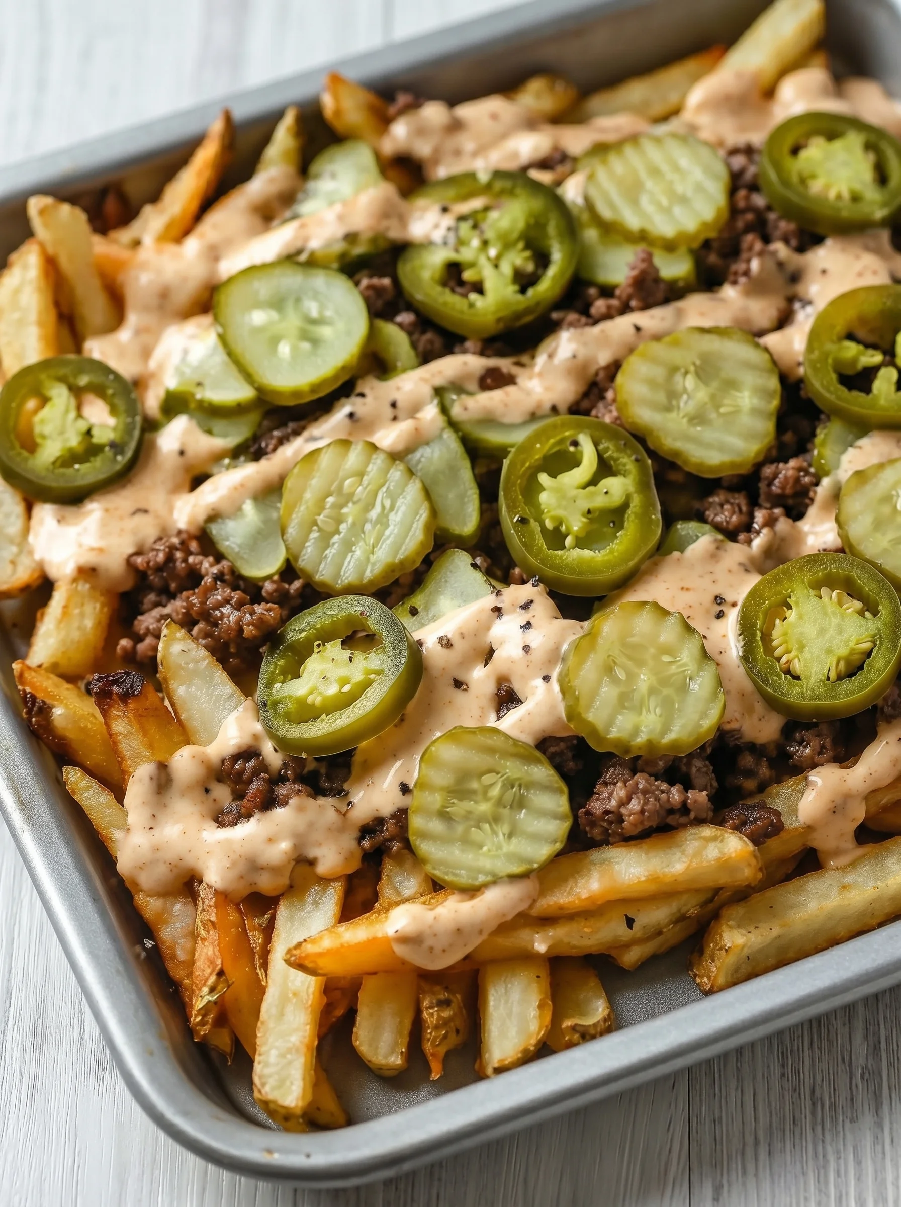 A plate of smash burger fries with a generous amount of sauce.