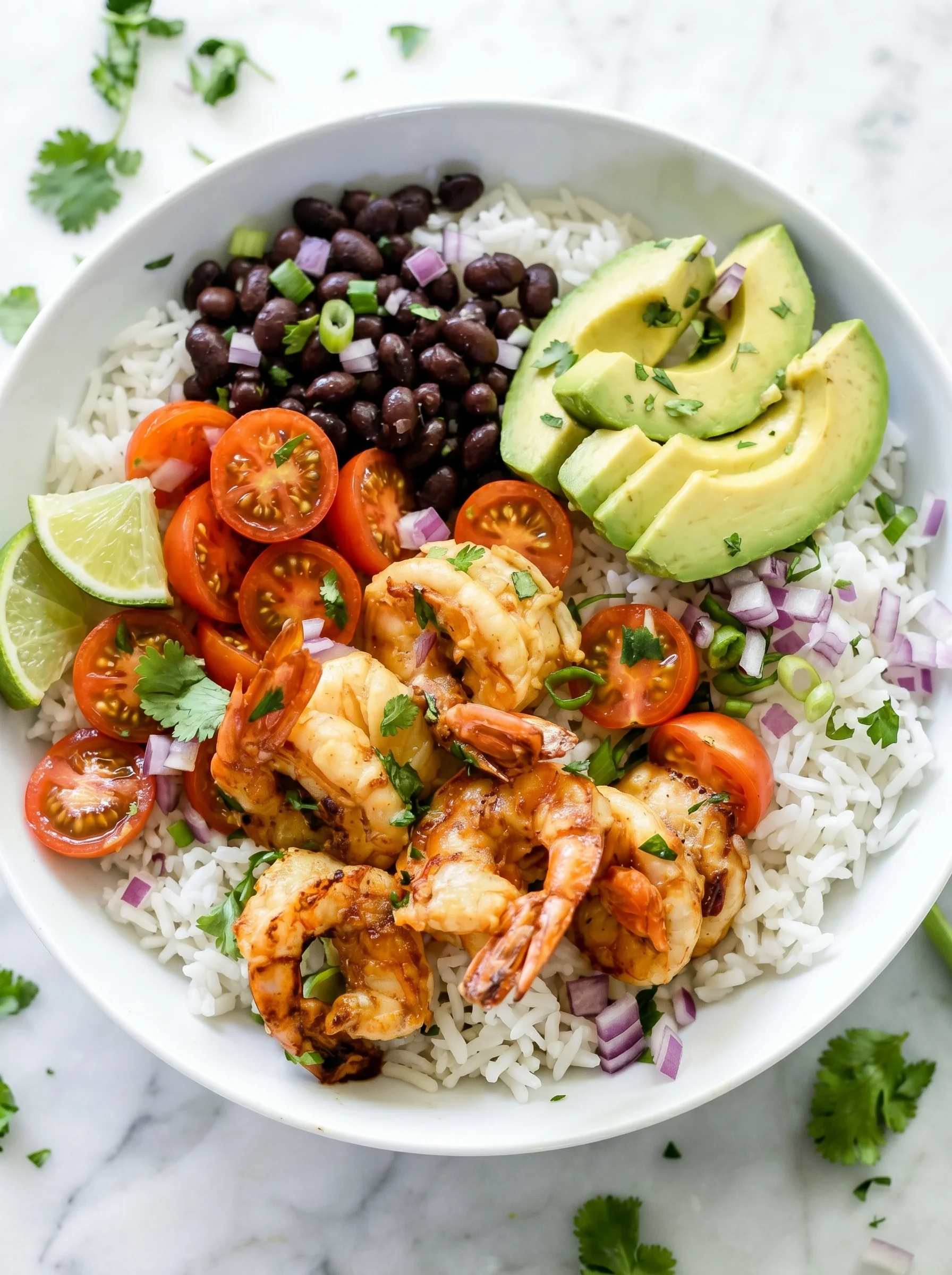 A bowl of shrimp, rice, tomatoes, avocado, and beans.