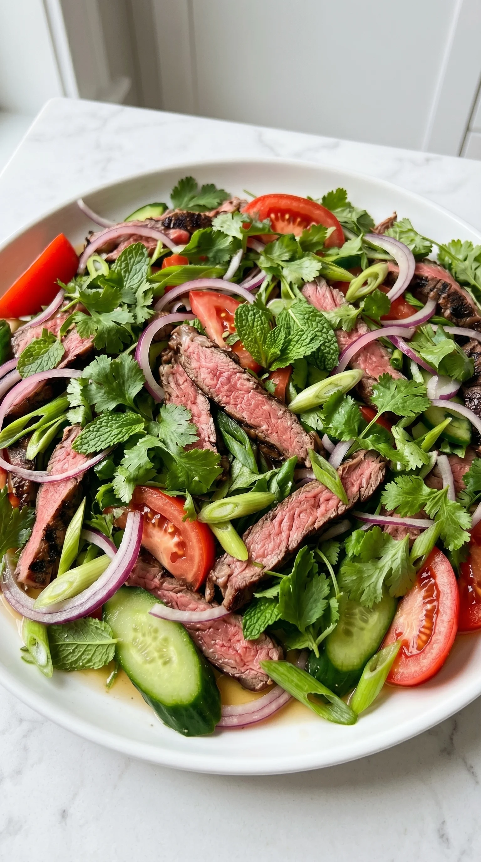 A Thai beef salad with onions, cucumbers, and tomatoes.