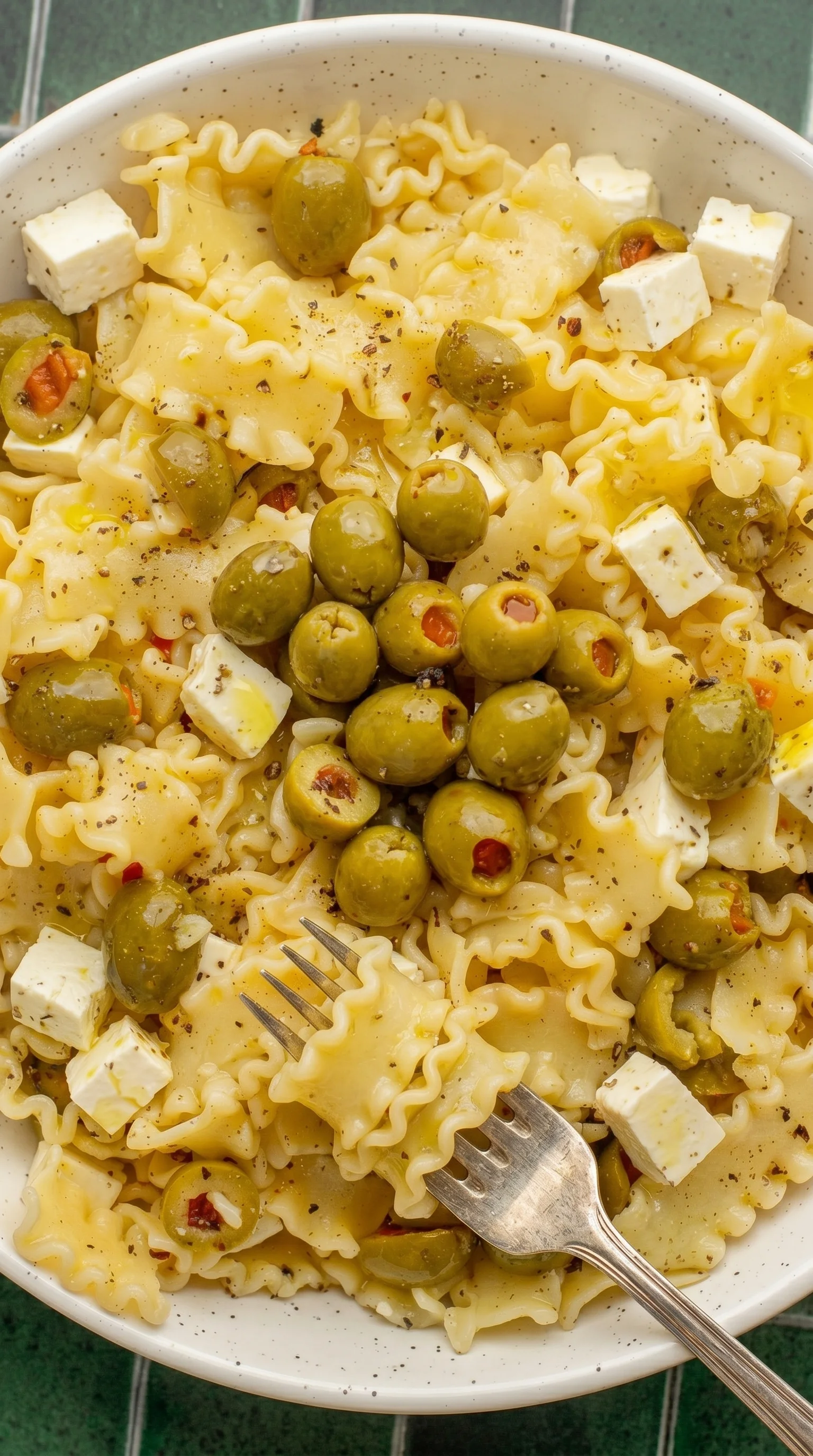 A delicious plate of pasta salad with olives and cheese.