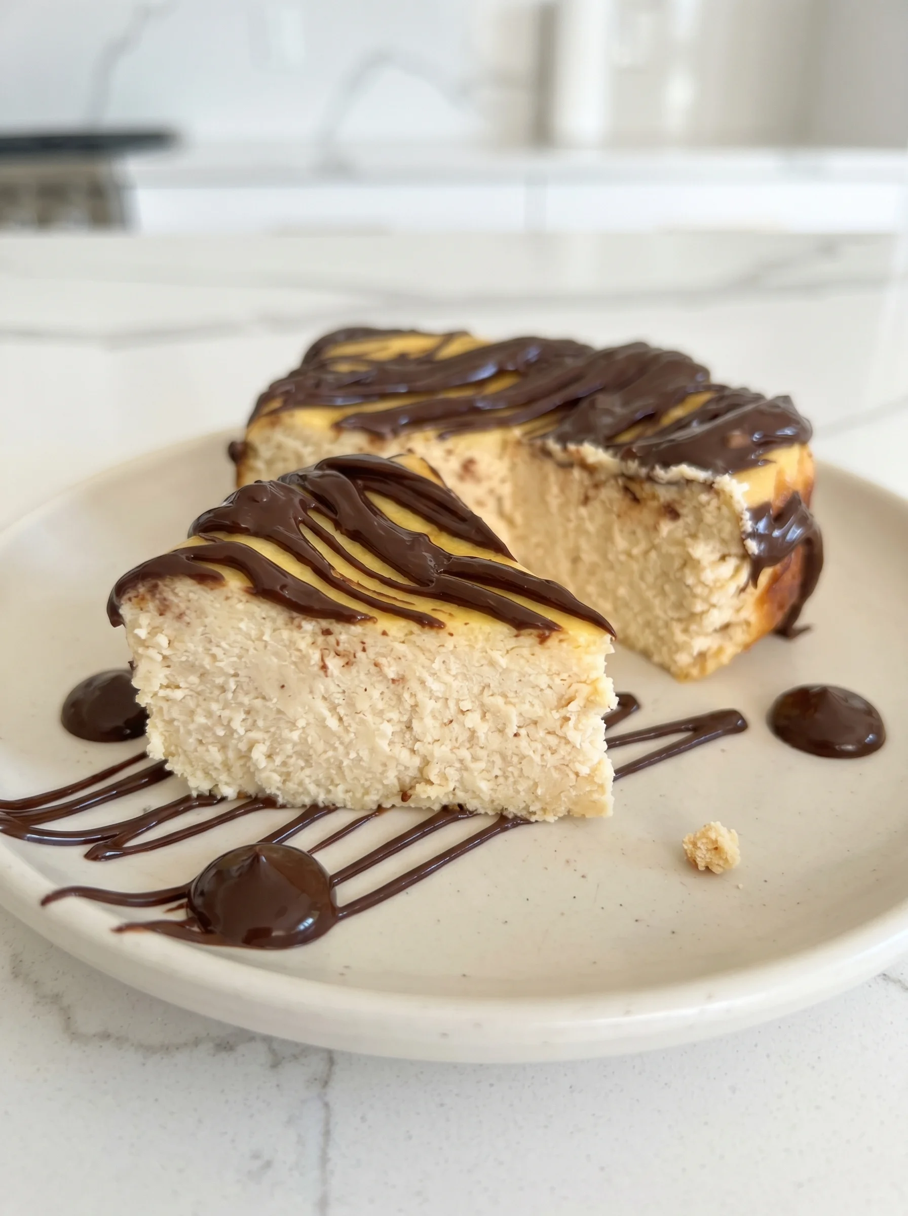 A slice of cheesecake with chocolate drizzle.