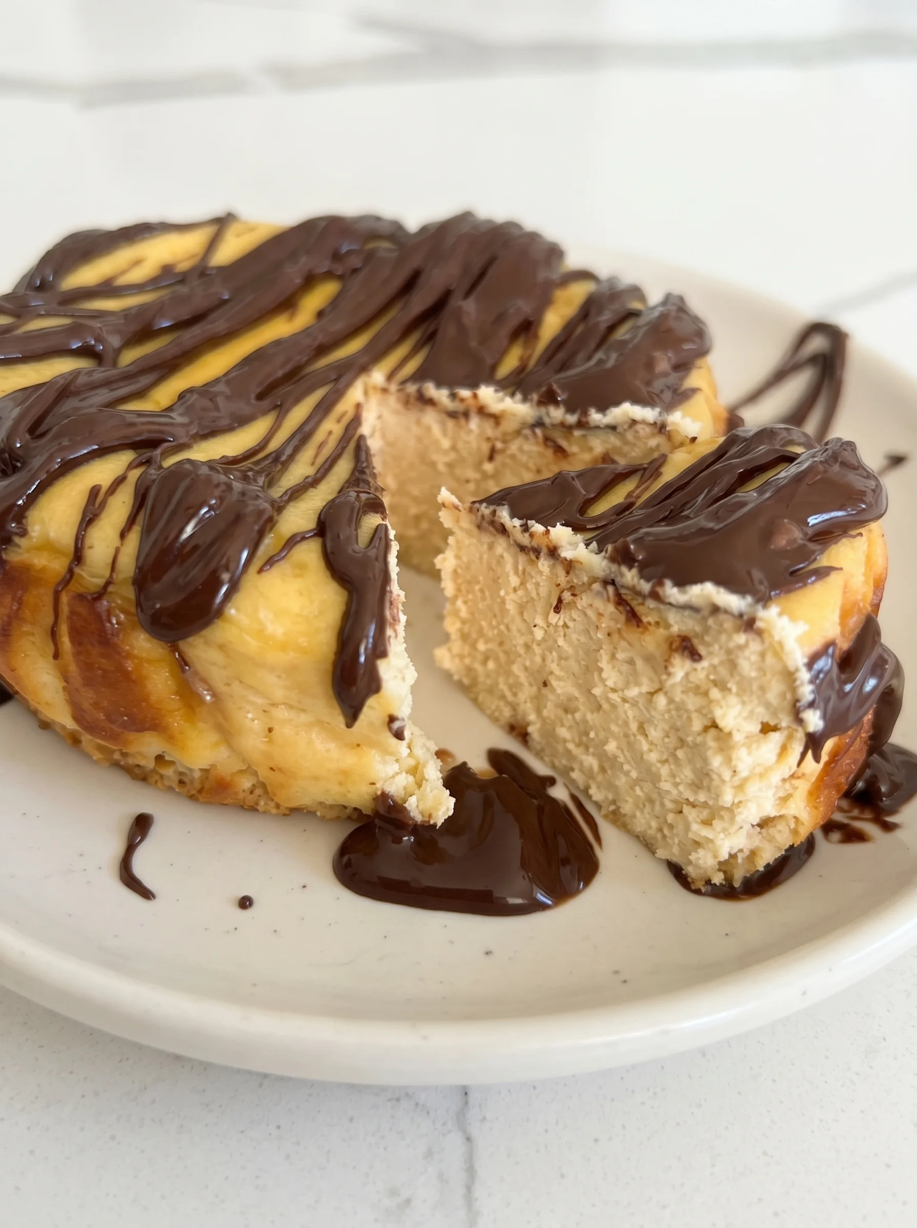A slice of healthy high protein cheesecake with chocolate drizzle.
