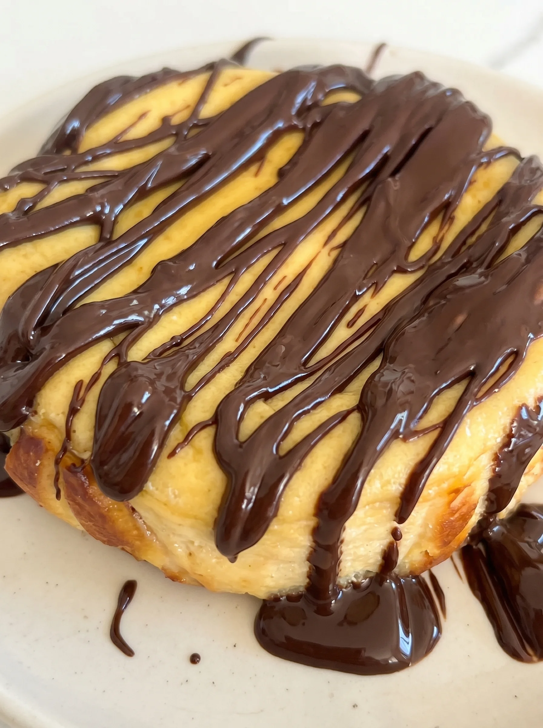 A slice of cheesecake with chocolate drizzled on top.