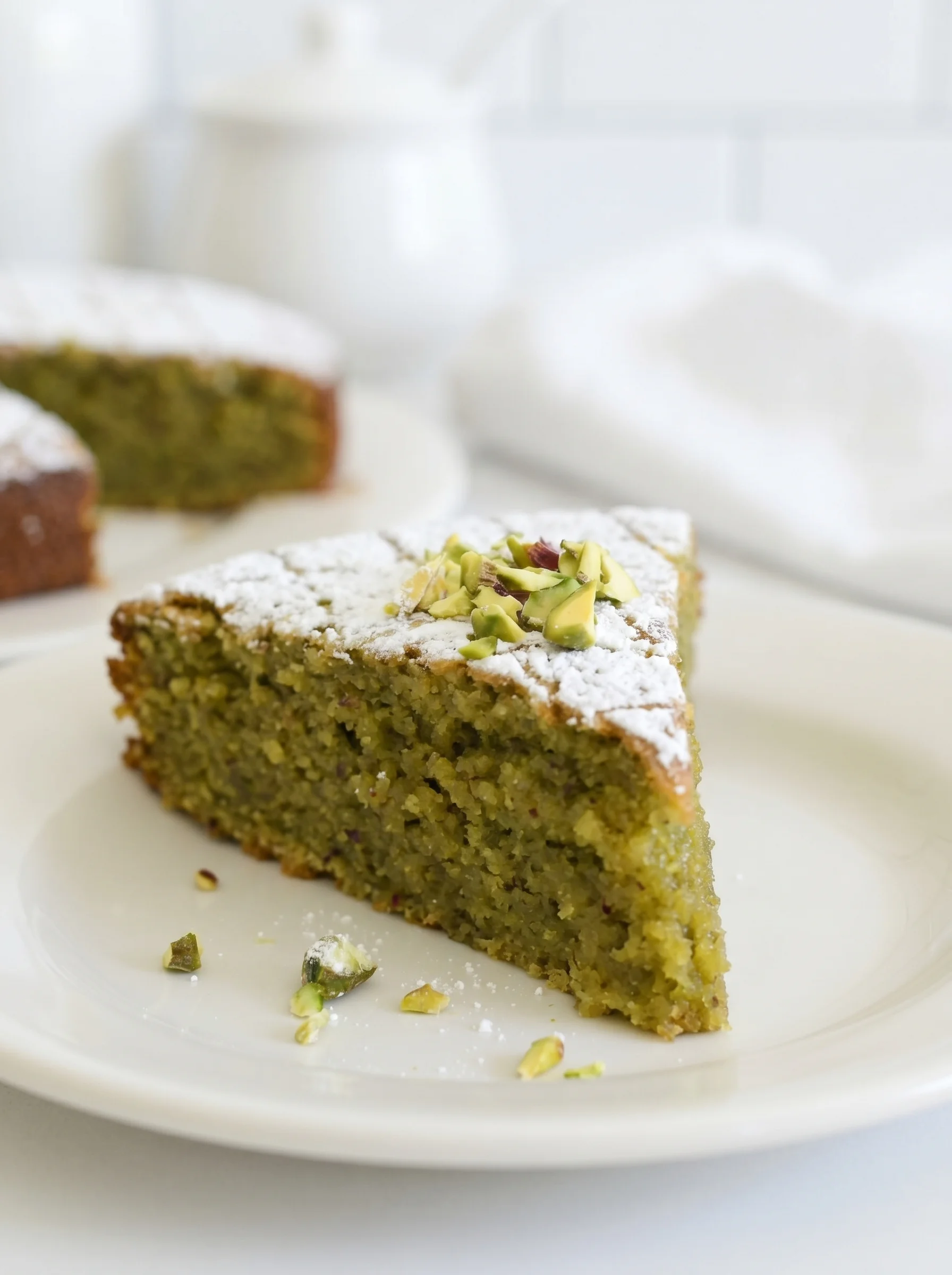 A yummy slice of pistachio torta caprese on a white plate.