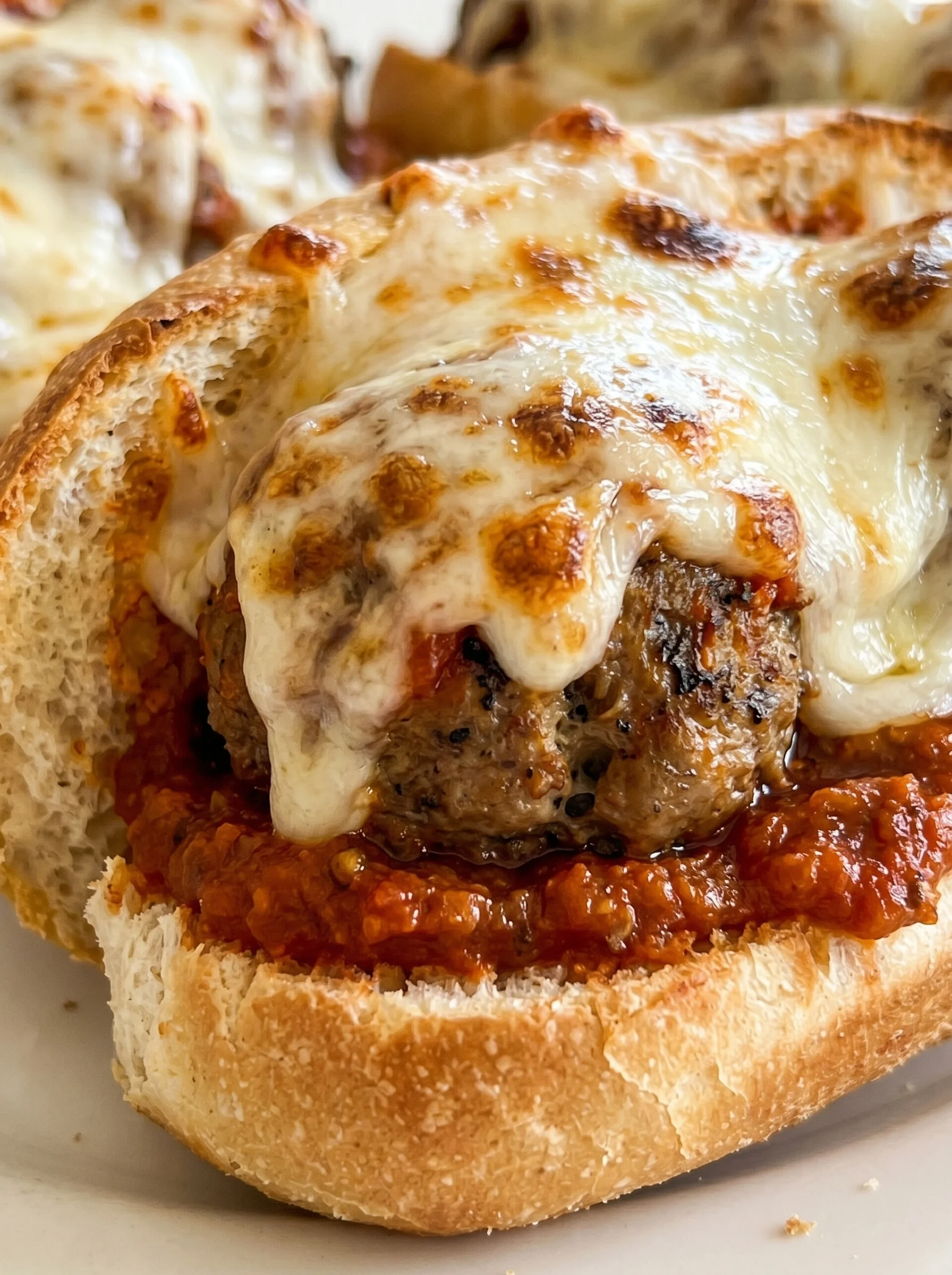 A meatball sub with cheese and tomato sauce.
