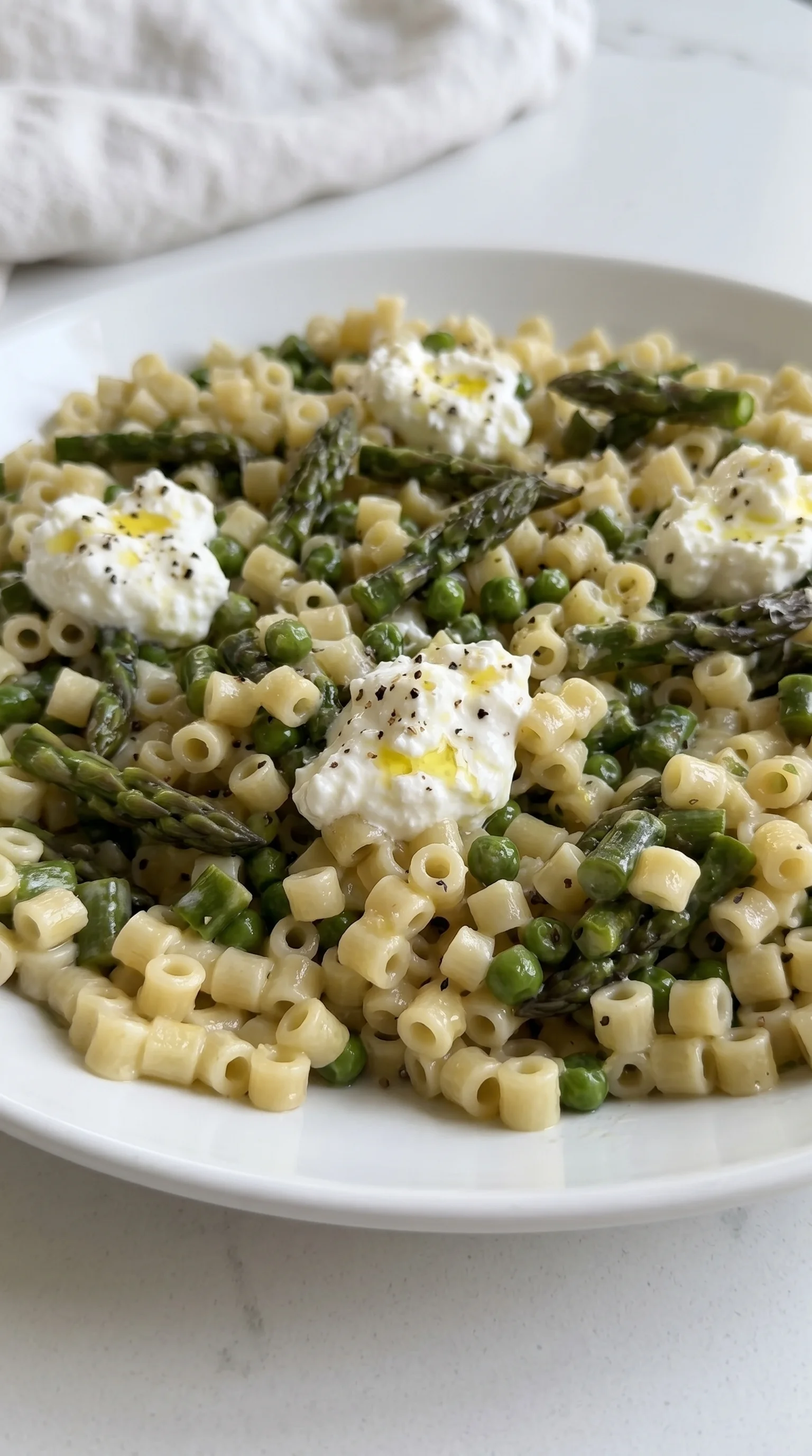 A plate of pasta with peas and asparagus.