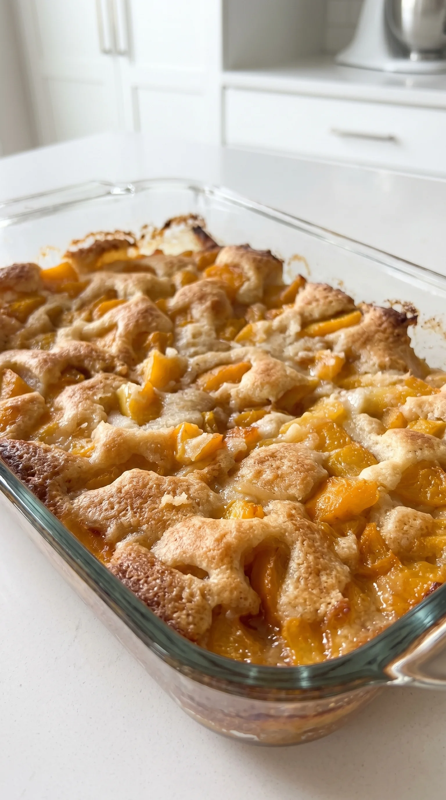 A glass dish filled with a peach cobbler dessert.