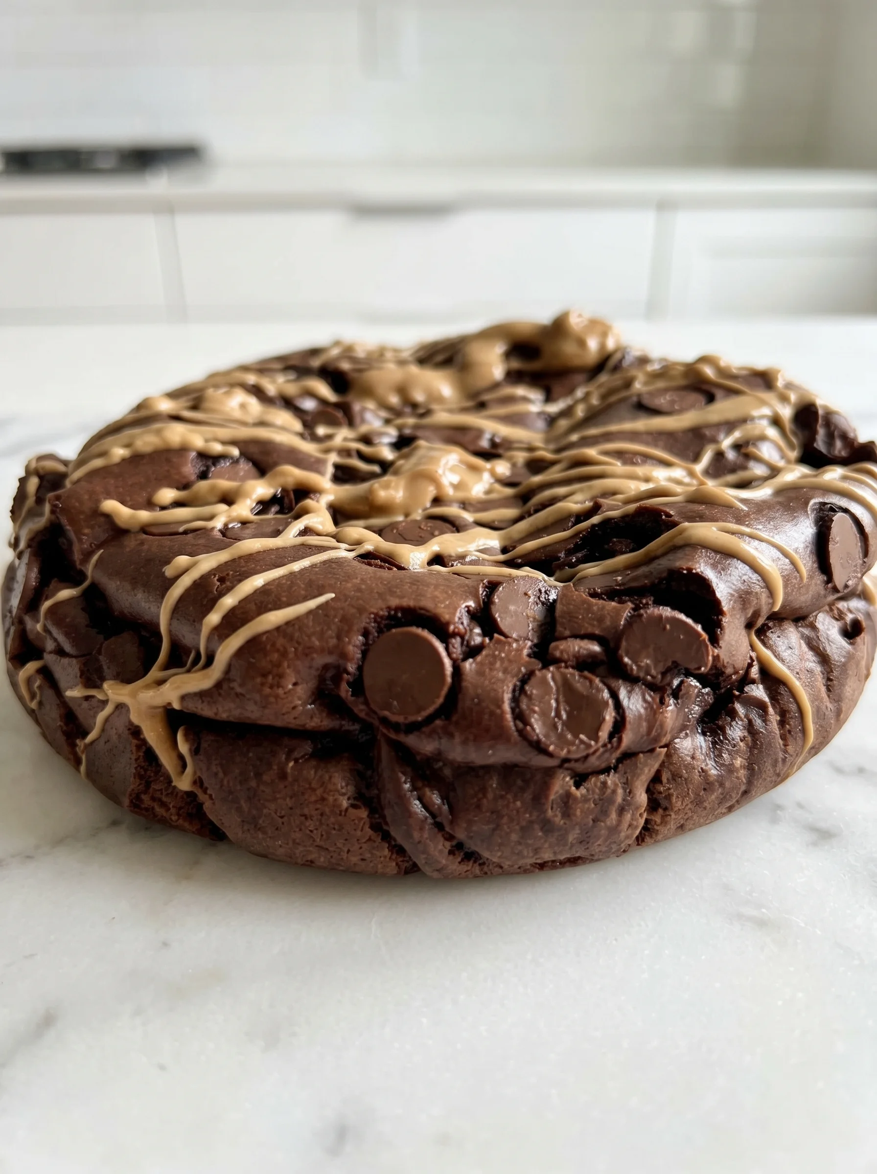 A chocolate cake with chocolate chips and caramel drizzle.