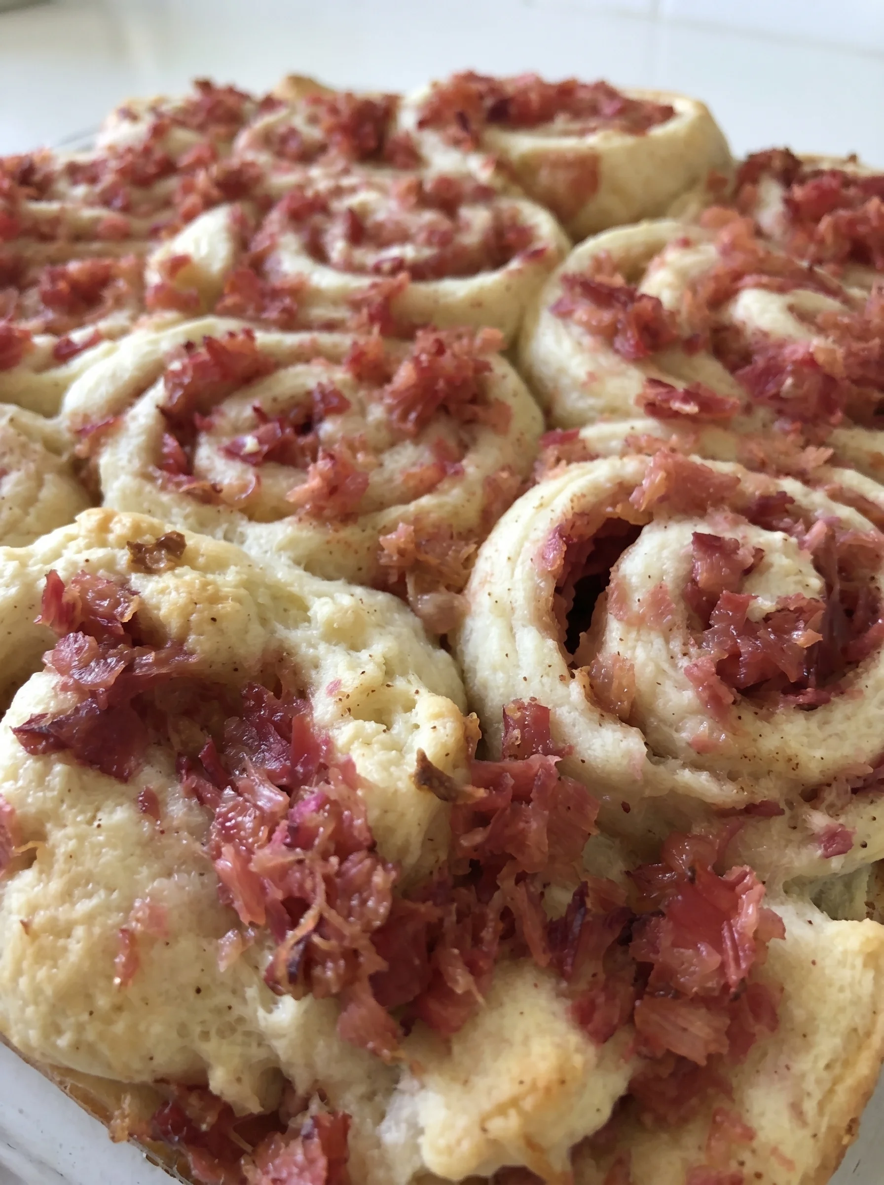 A close up of a pastry with bacon and a red filling.