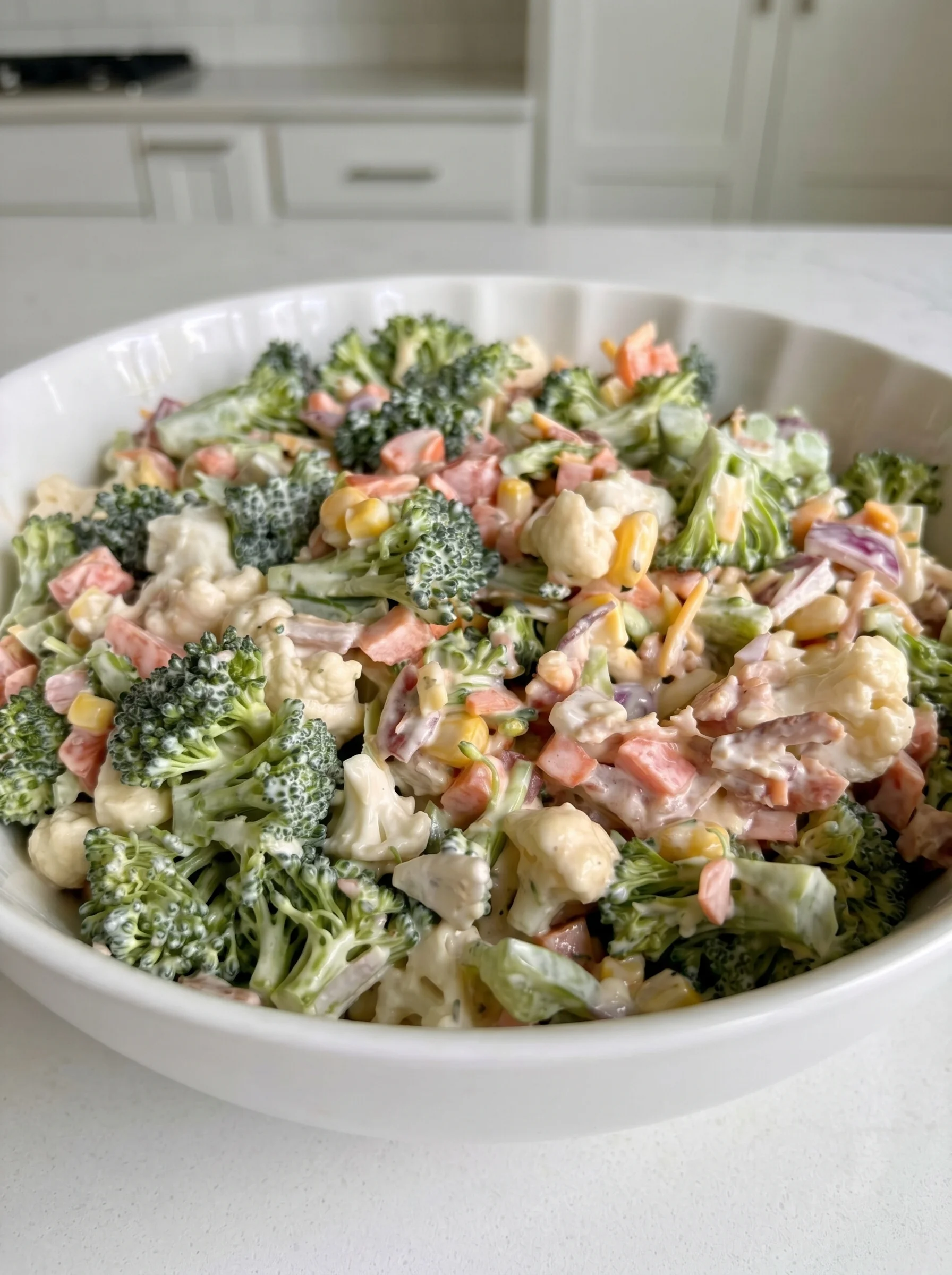 A bowl of chopped salad with broccoli and bacon.