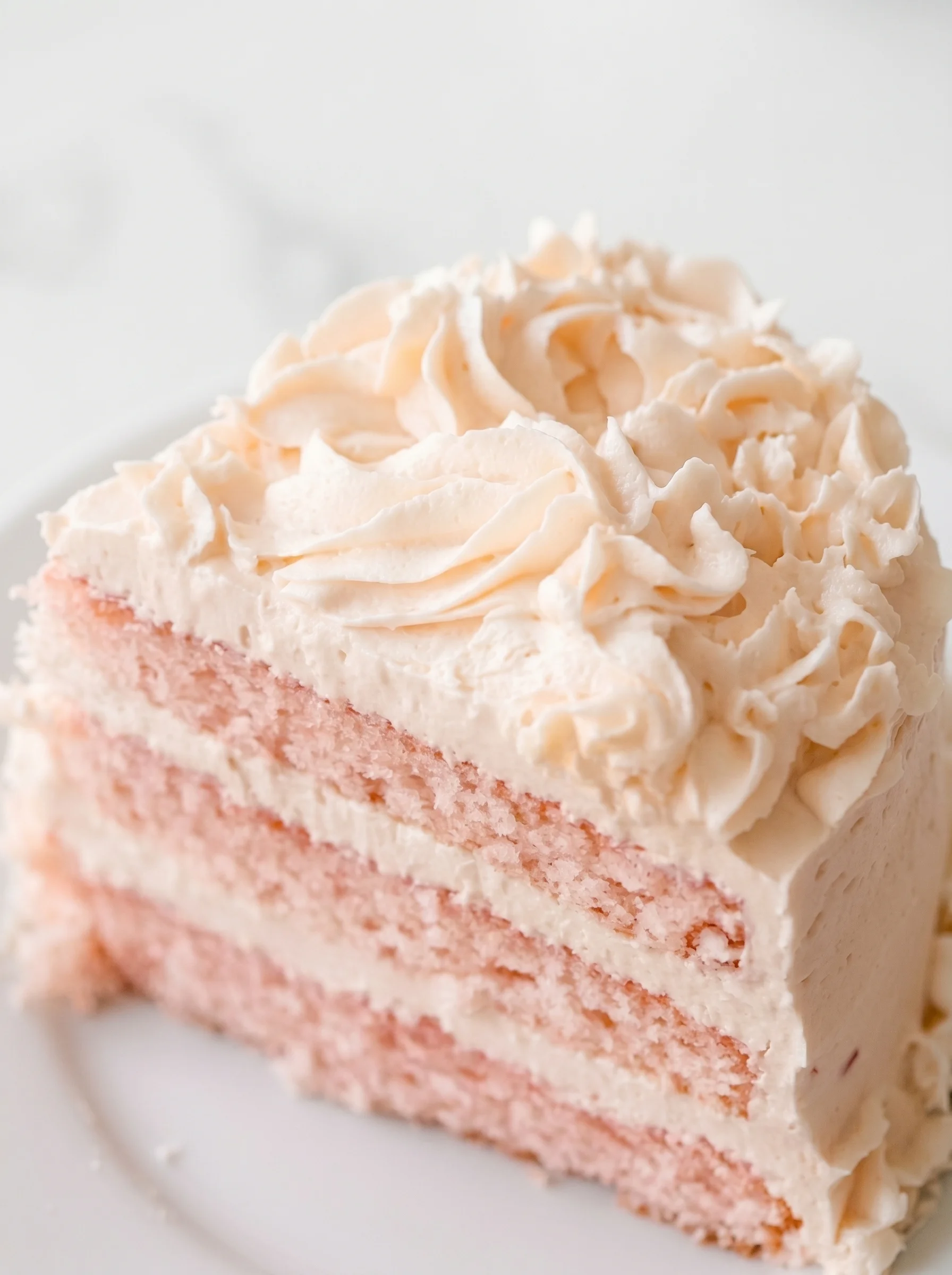 A slice of pink cake with white frosting.