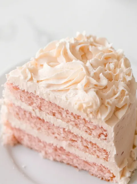 A slice of pink cake with white frosting.