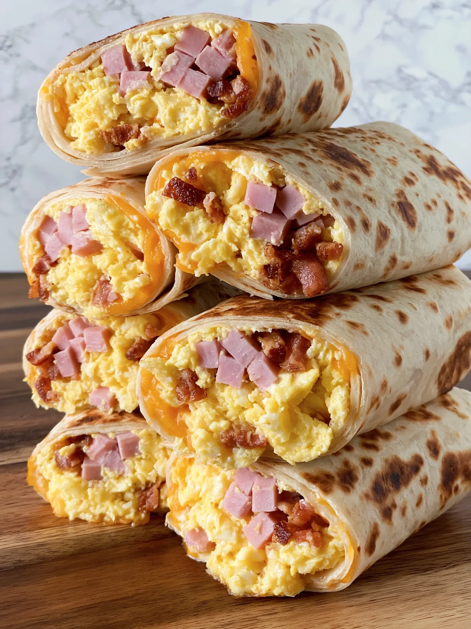A stack of breakfast burritos with bacon and eggs.