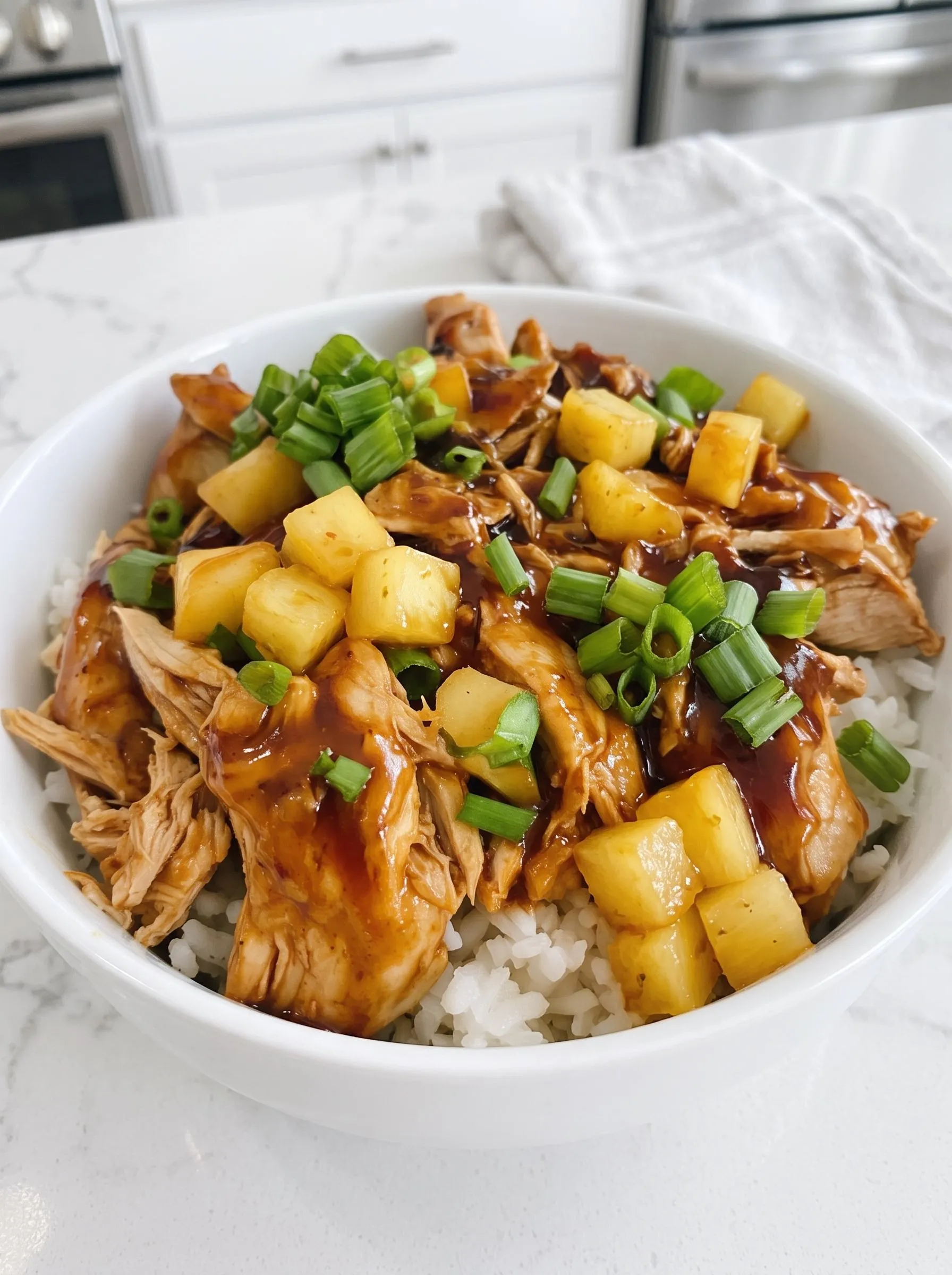 A bowl of chicken with pineapple and sauce.
