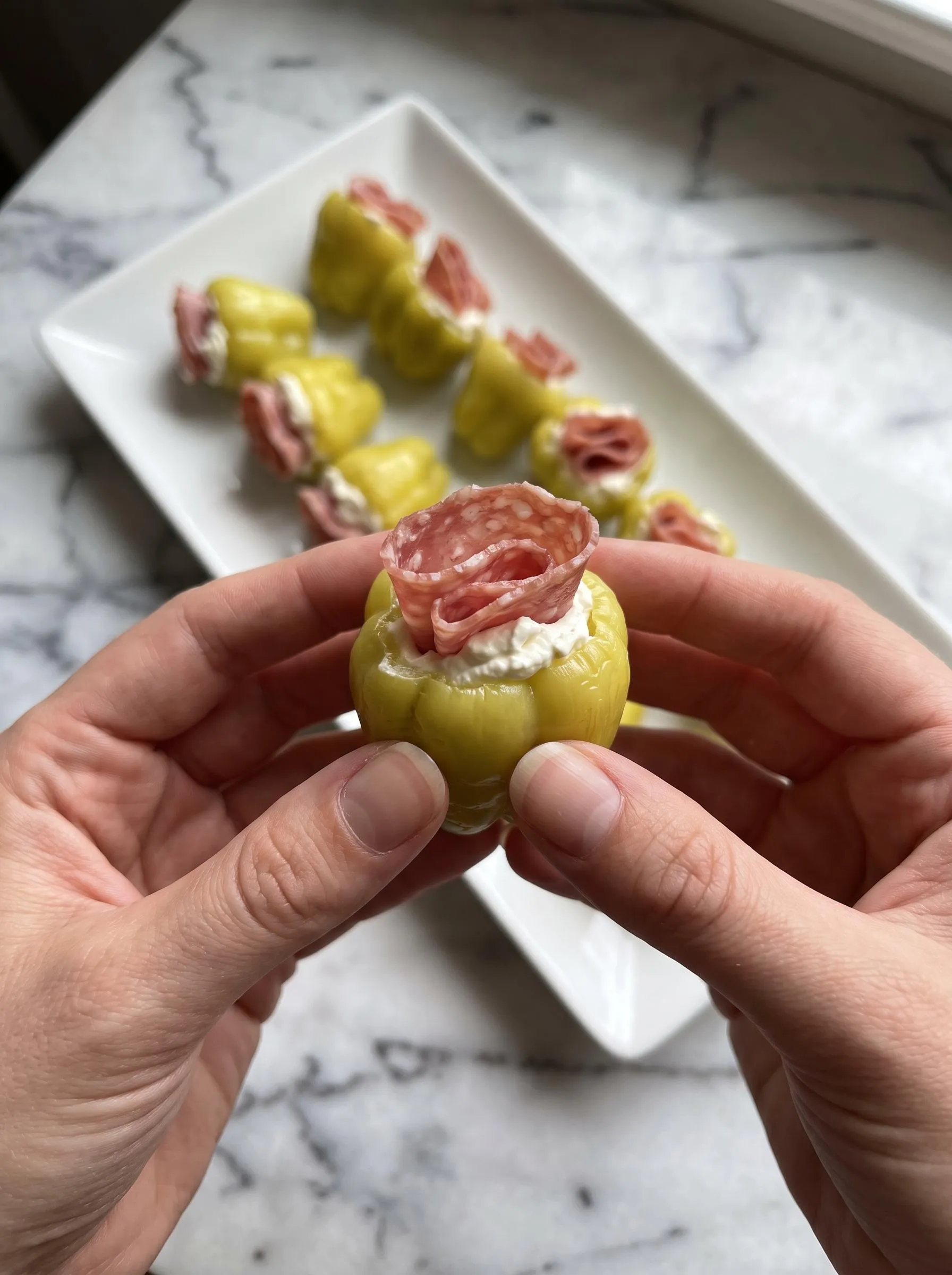 A person holding a stuffed pepperoncini.