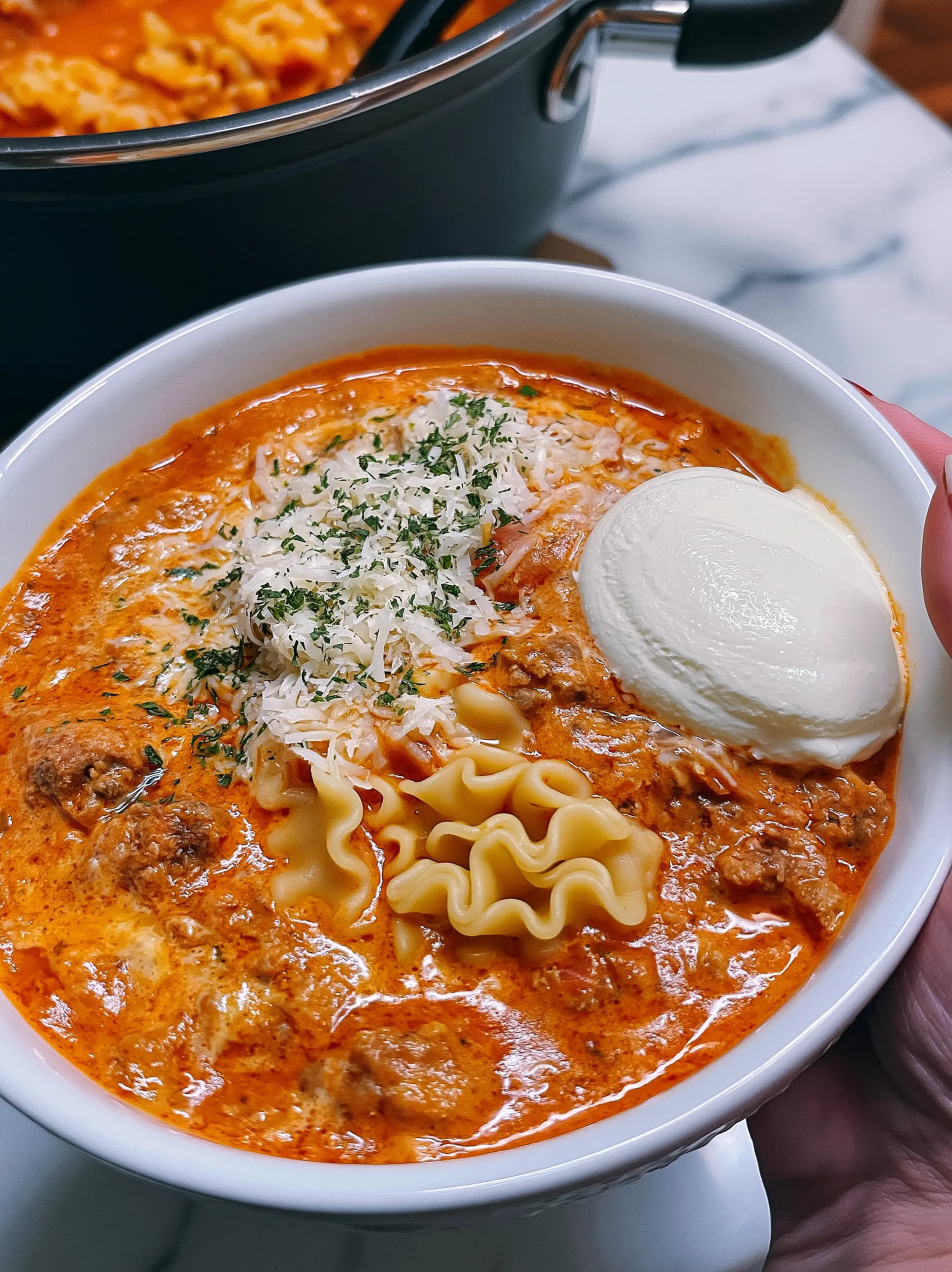A bowl of soup with noodles and cheese.