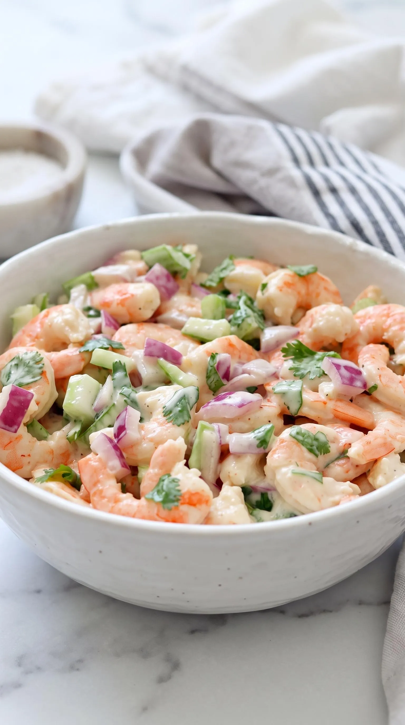 A bowl of shrimp salad with vegetables.