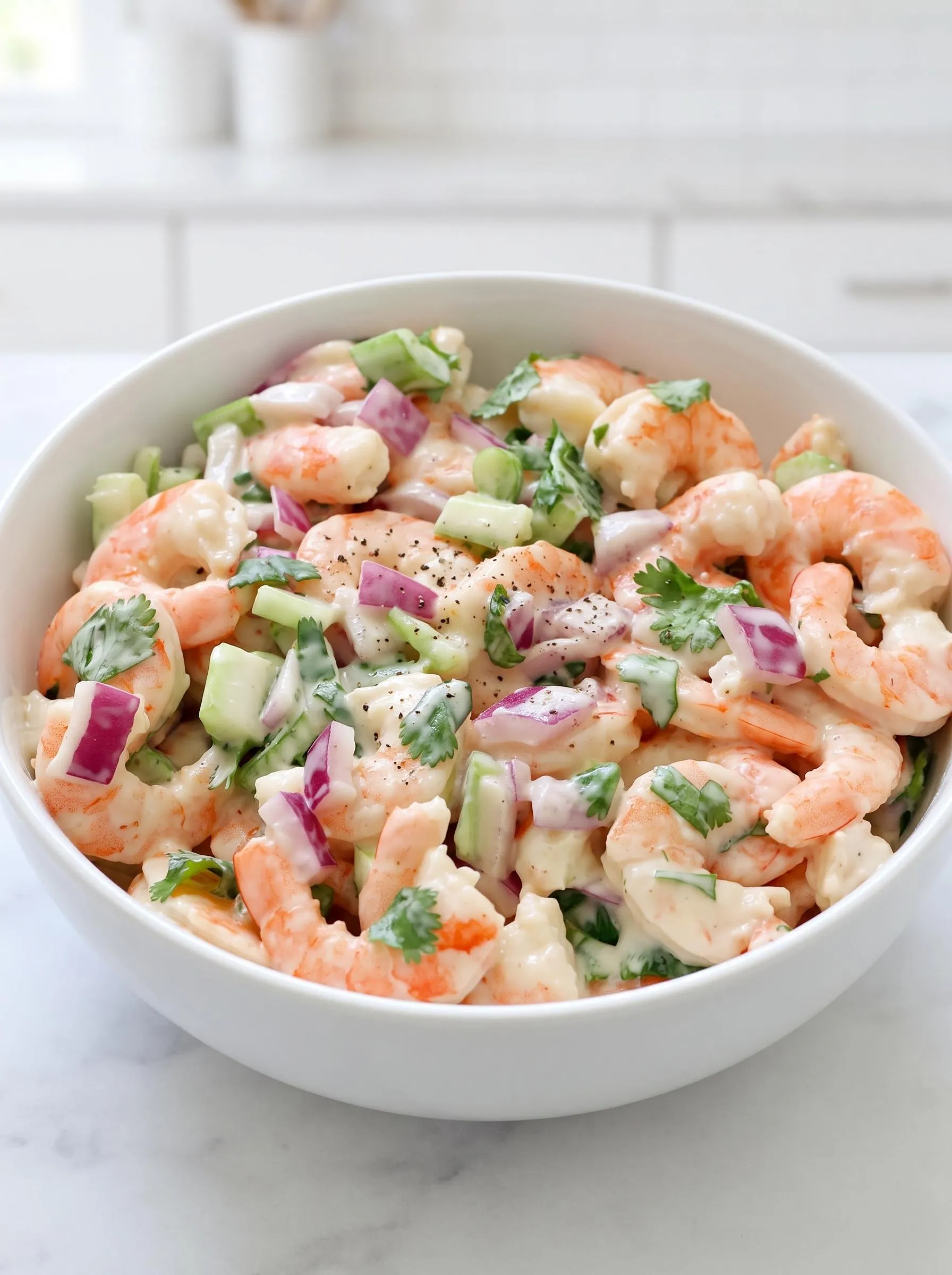 A bowl of shrimp salad with onions and cucumbers.