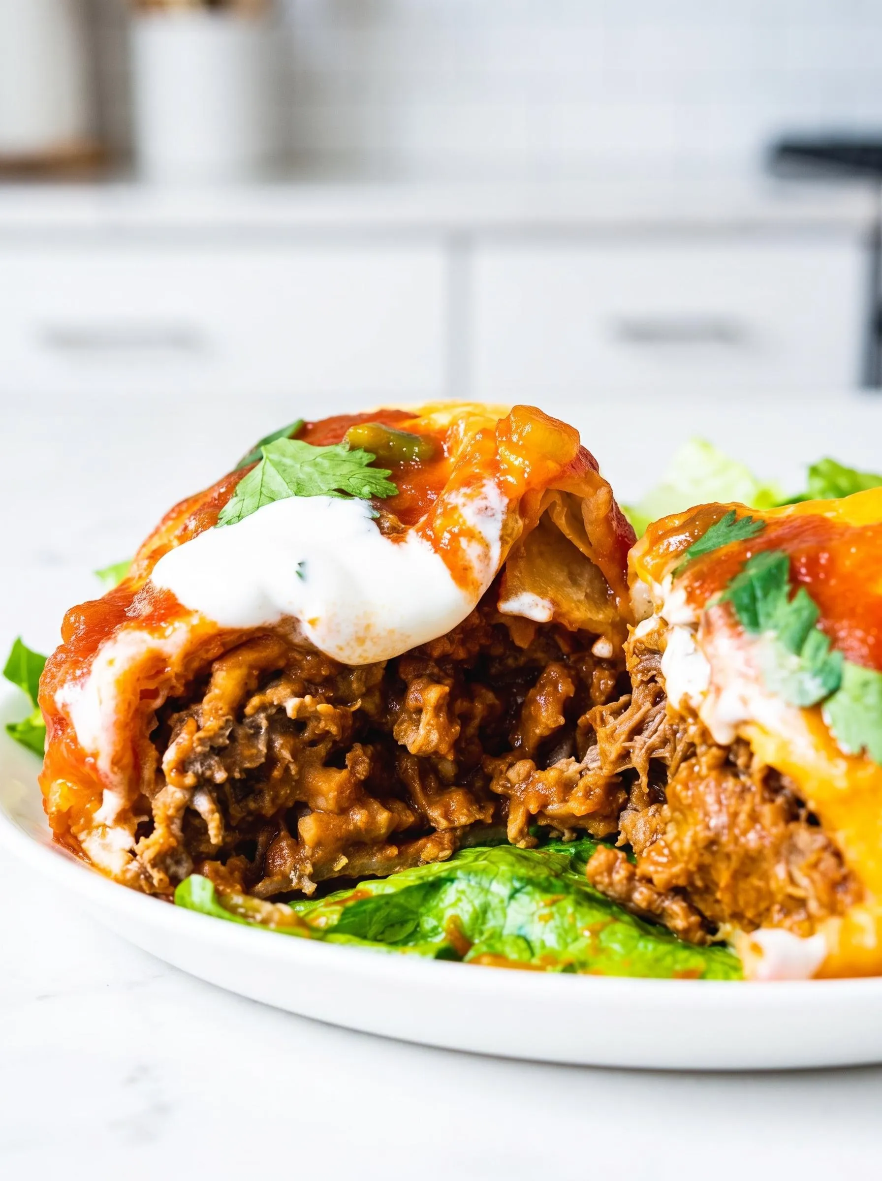 A plate of beef chimichangas with lettuce and sour cream.