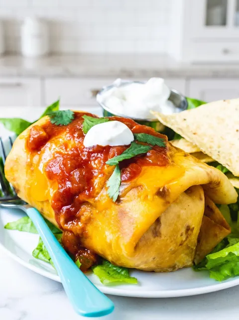 A plate of food with a beef chimichanga and a side of chips.