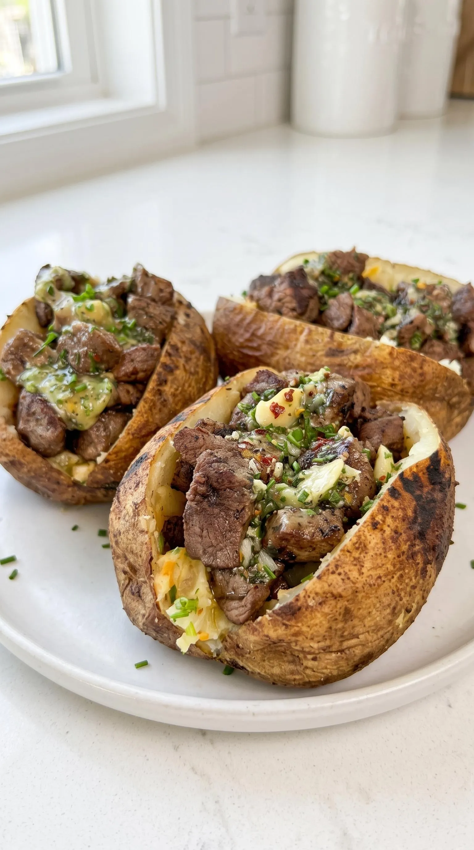 A plate of grilled steak bites and loaded baked potatoes.