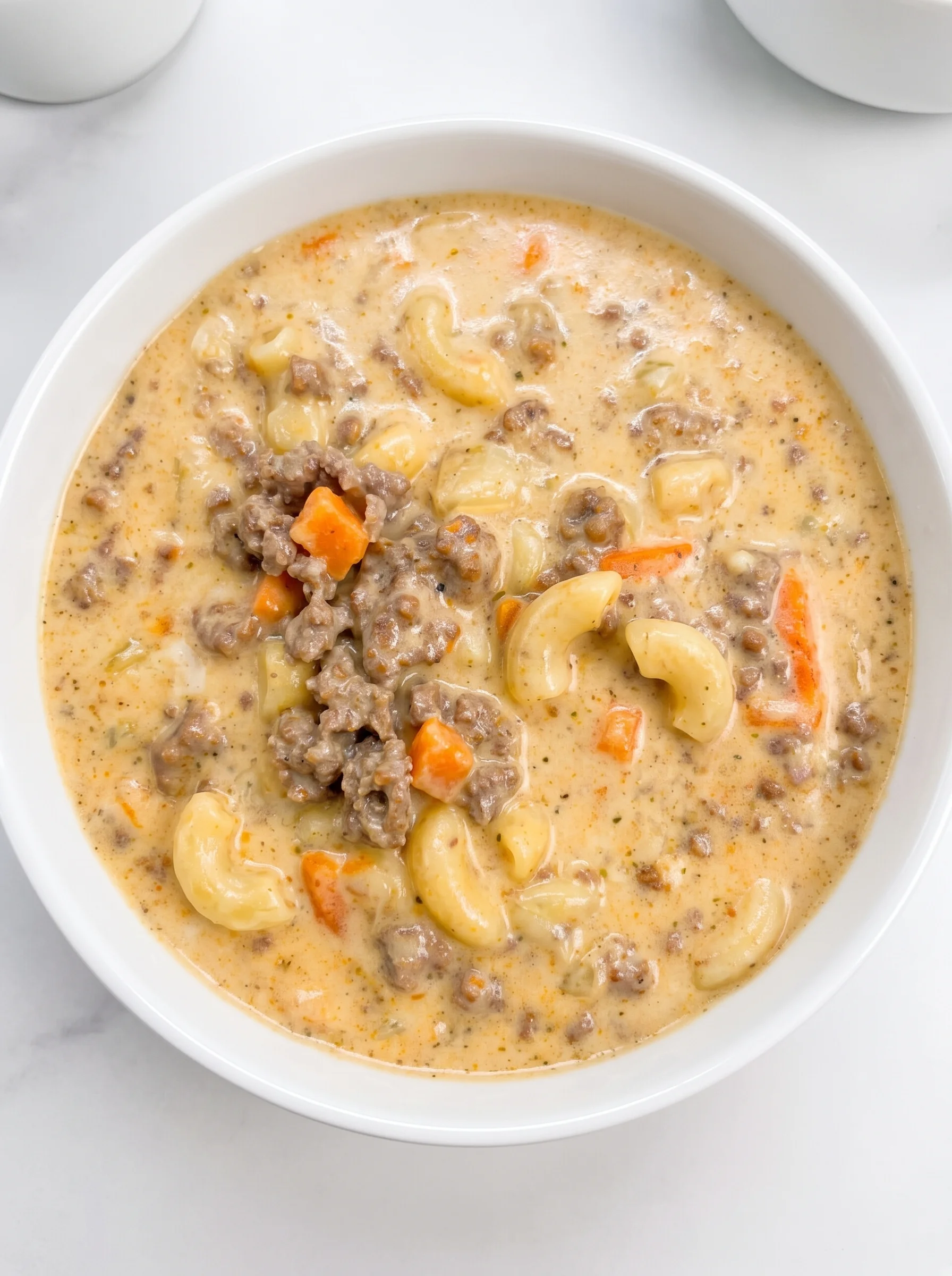 A cheeseburger macaroni soup in a white bowl.