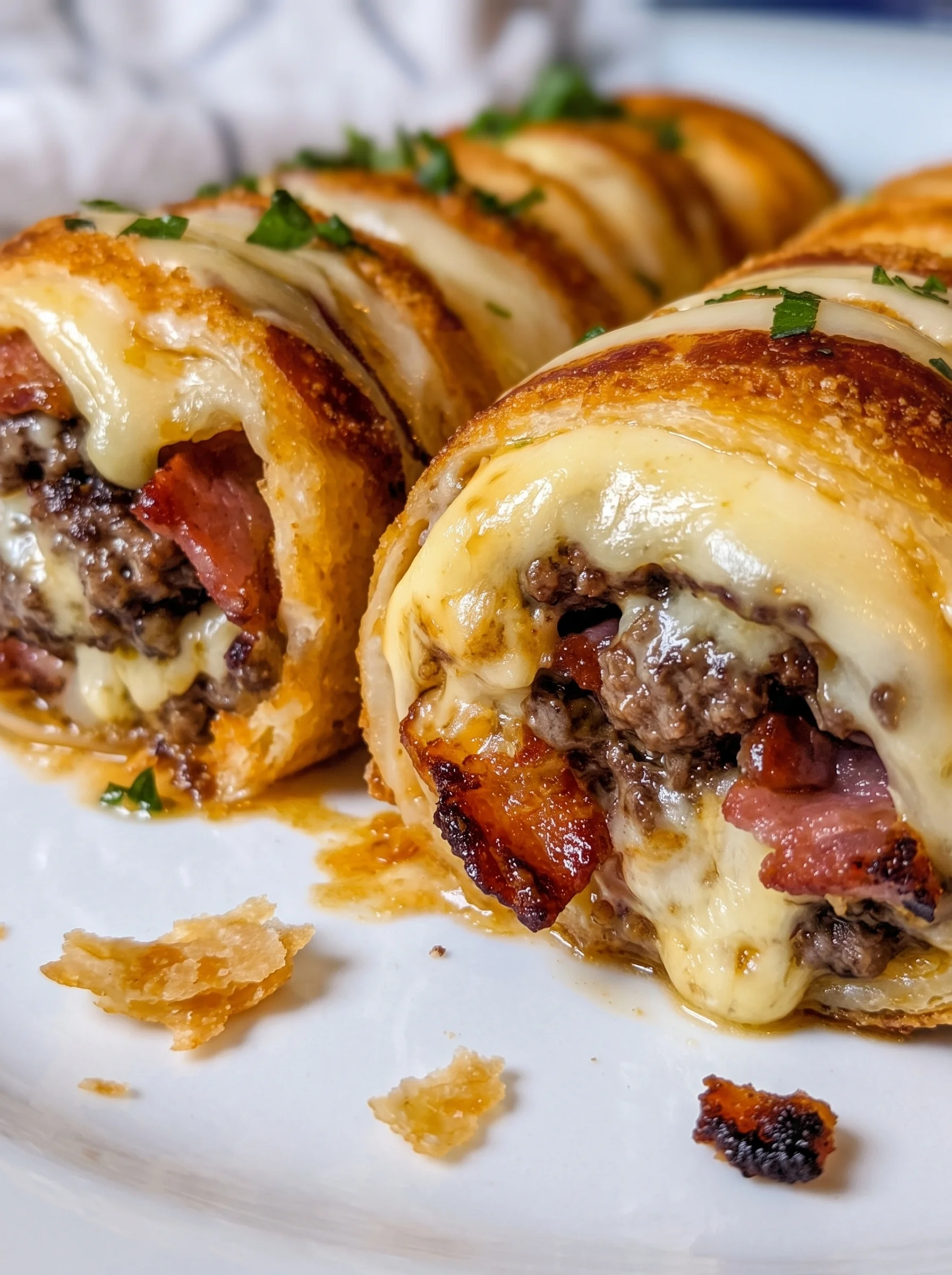 Bacon cheeseburger rollups on a white plate.