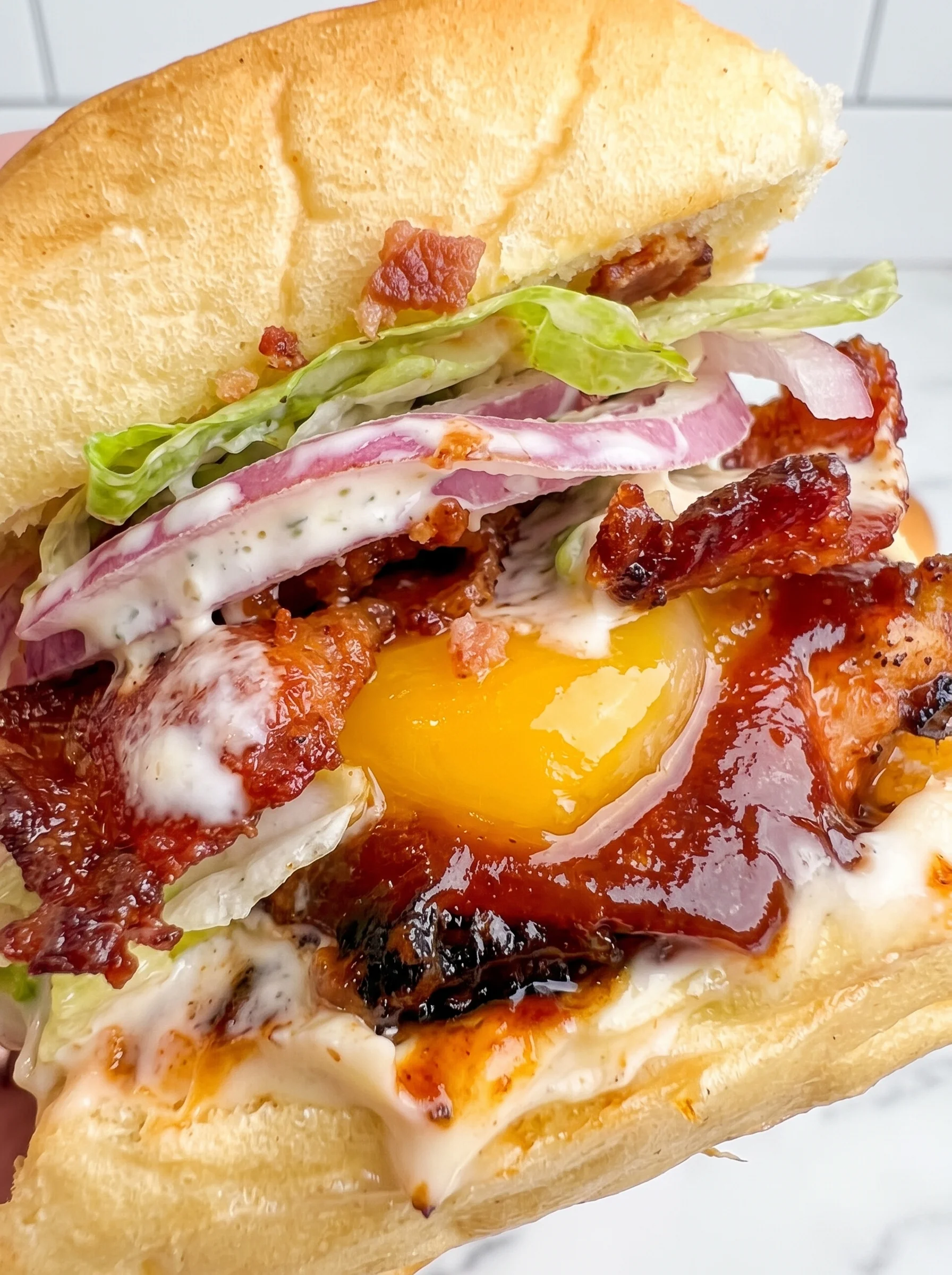 A close up of a bacon ranch BBQ chicken slider.