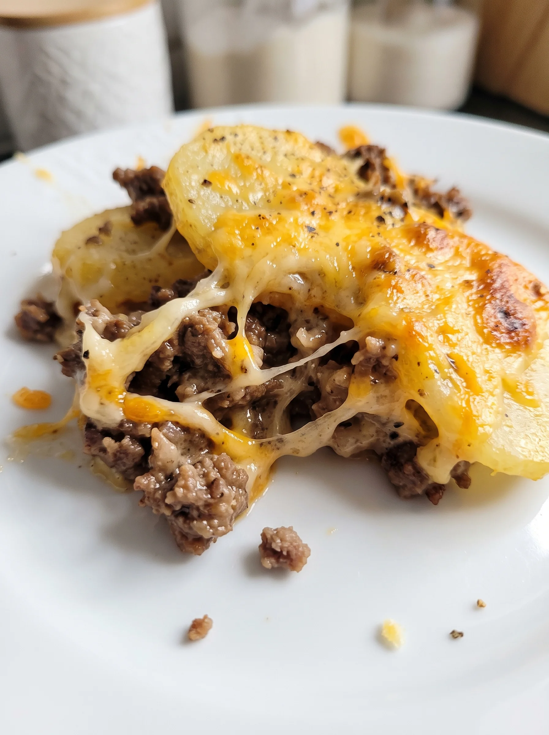 A cheesy hamburger potato on a plate.